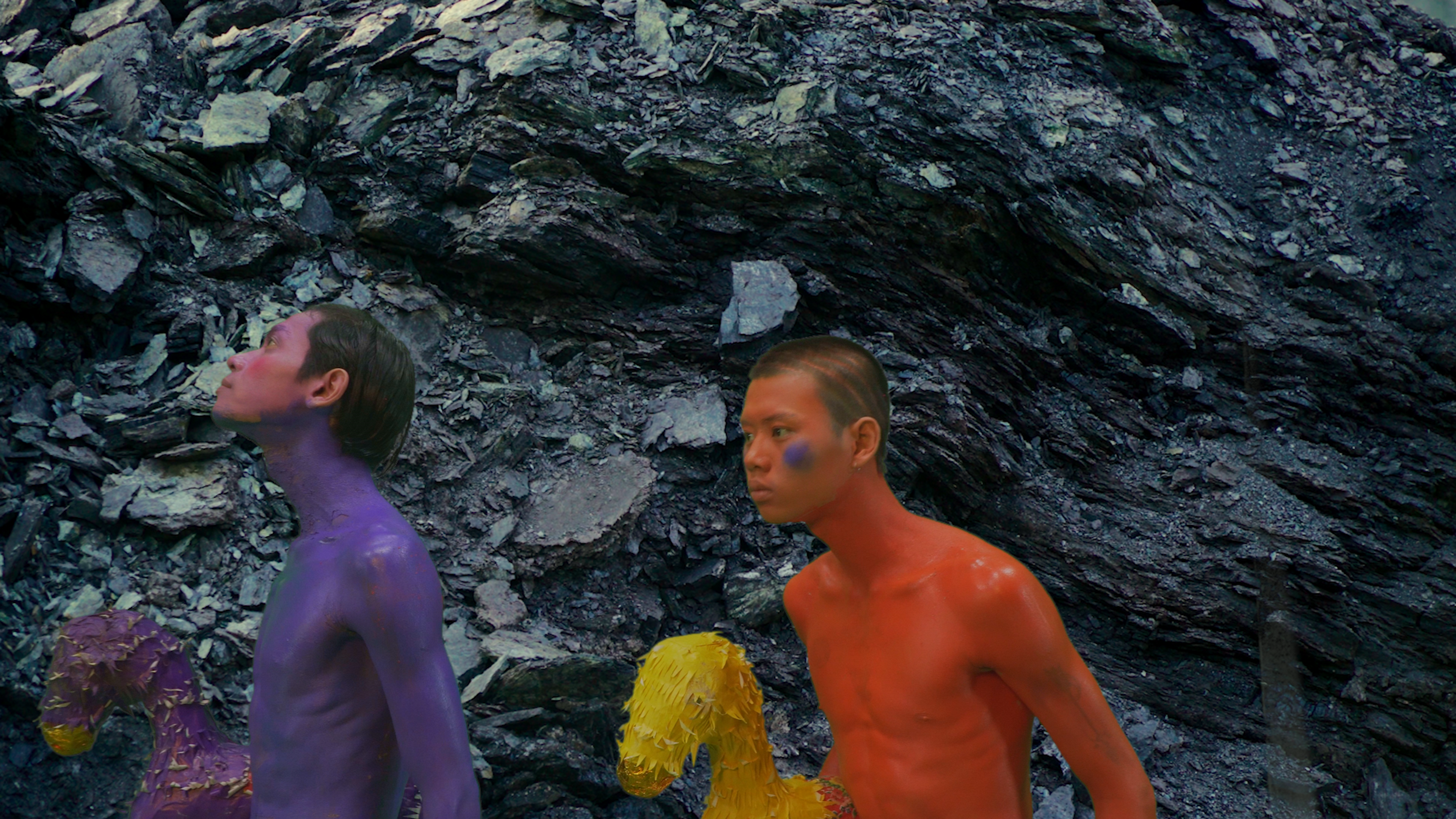 A purple figure and an orange figure against a background of rocks.