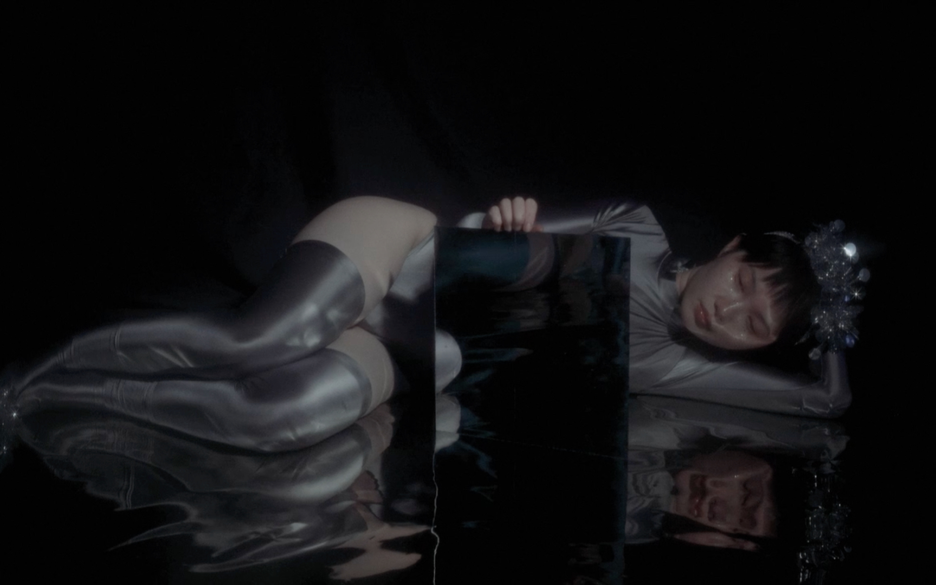A figure wearing silver clothes lying on the floor.