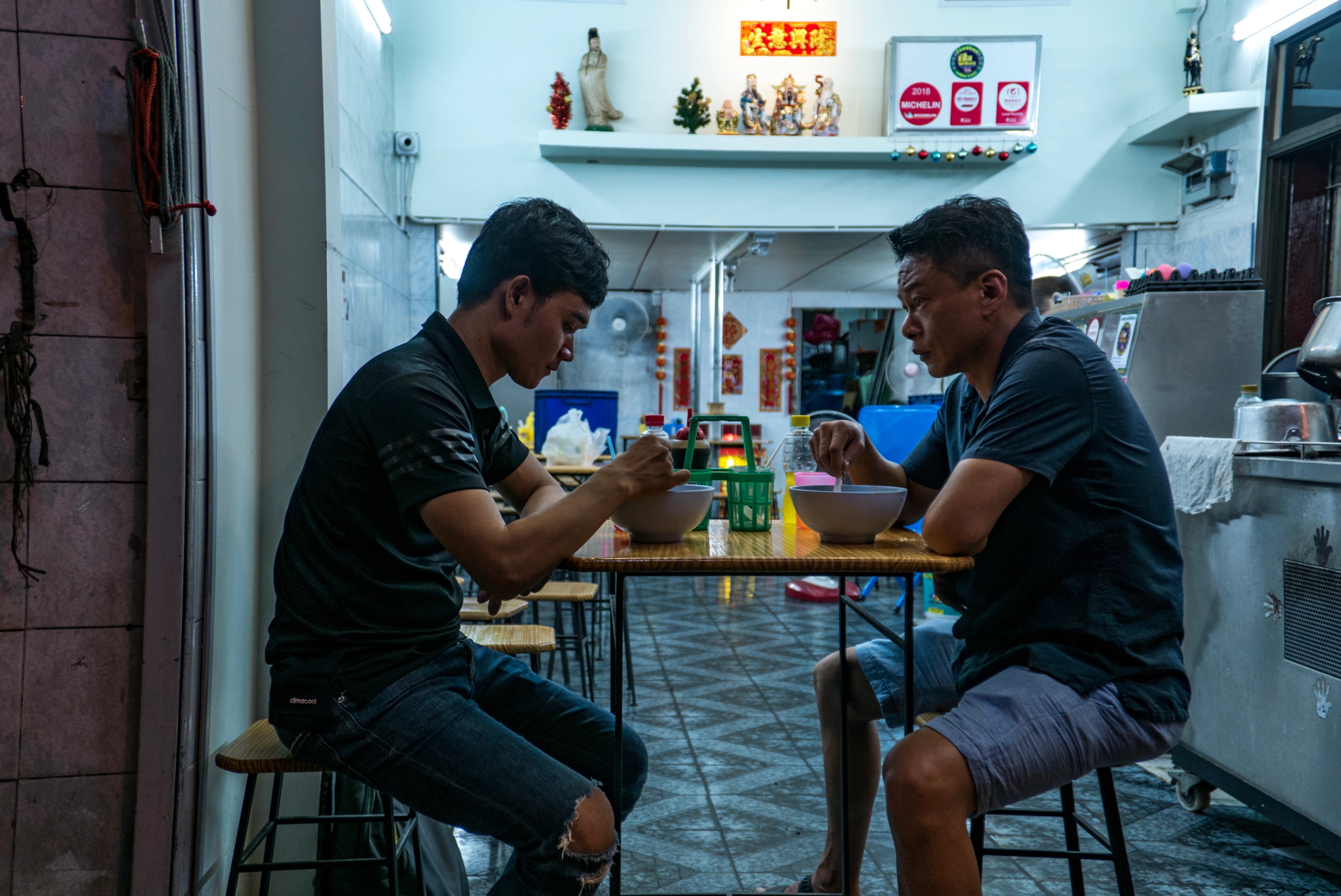 Two men seating facing each other while eating.