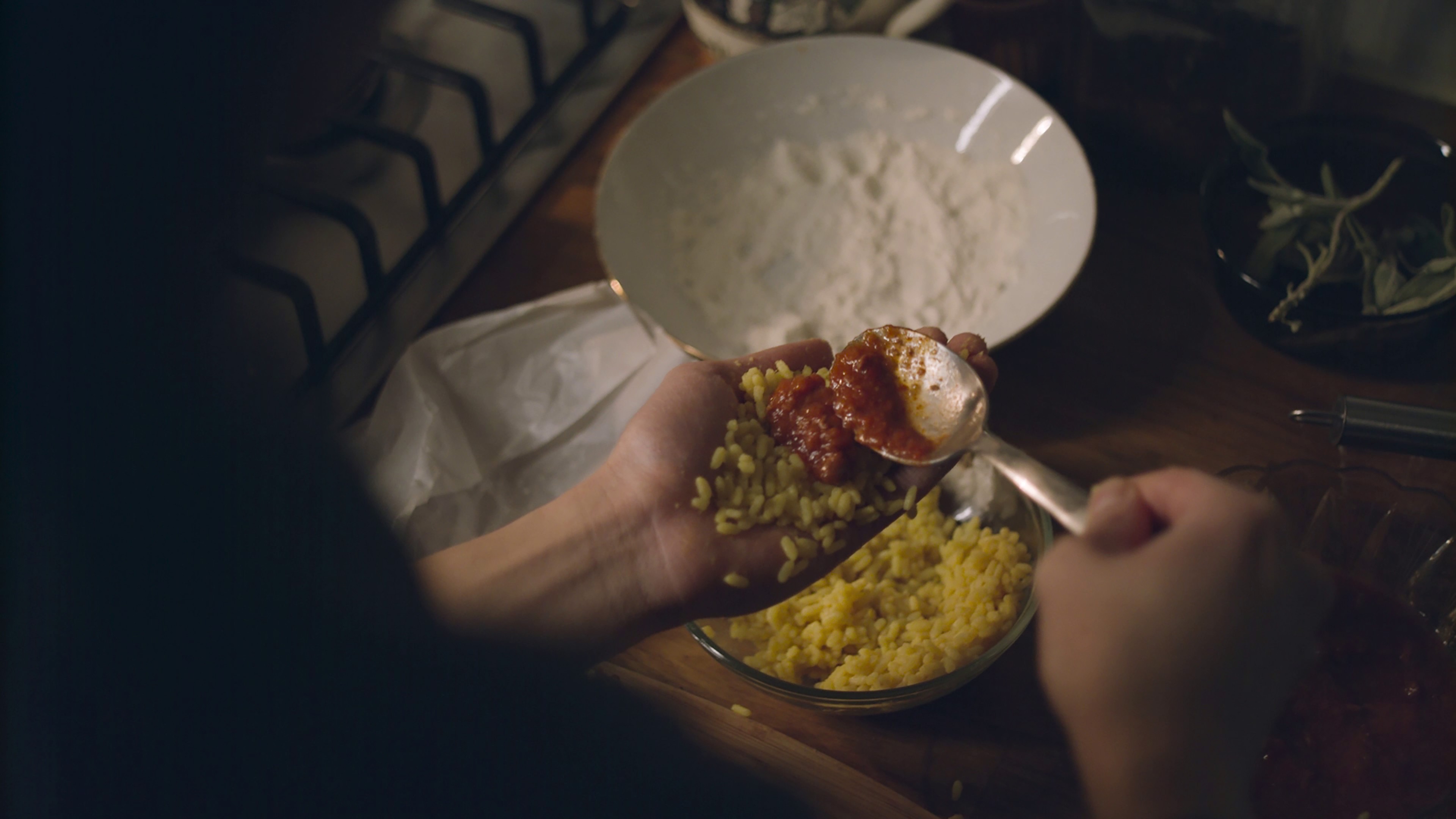 Hands holding rice, sauce, and a spoon.