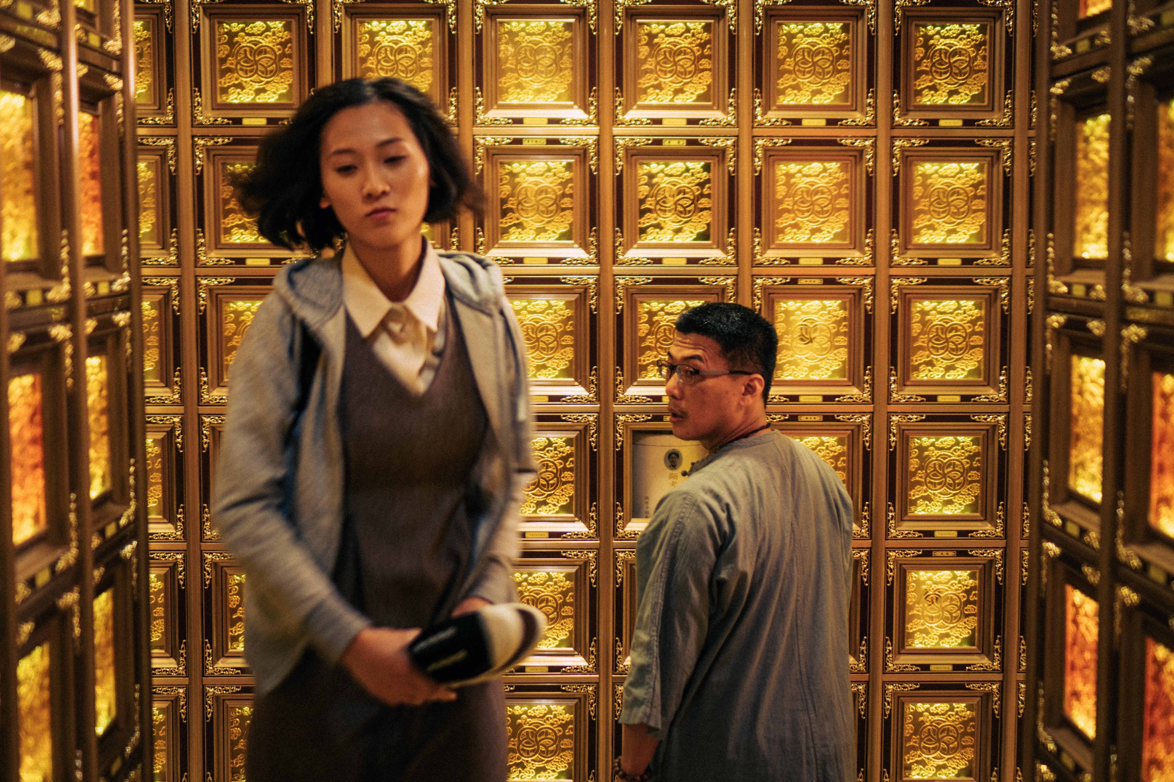 Two figures in a room decorated with gold panels.