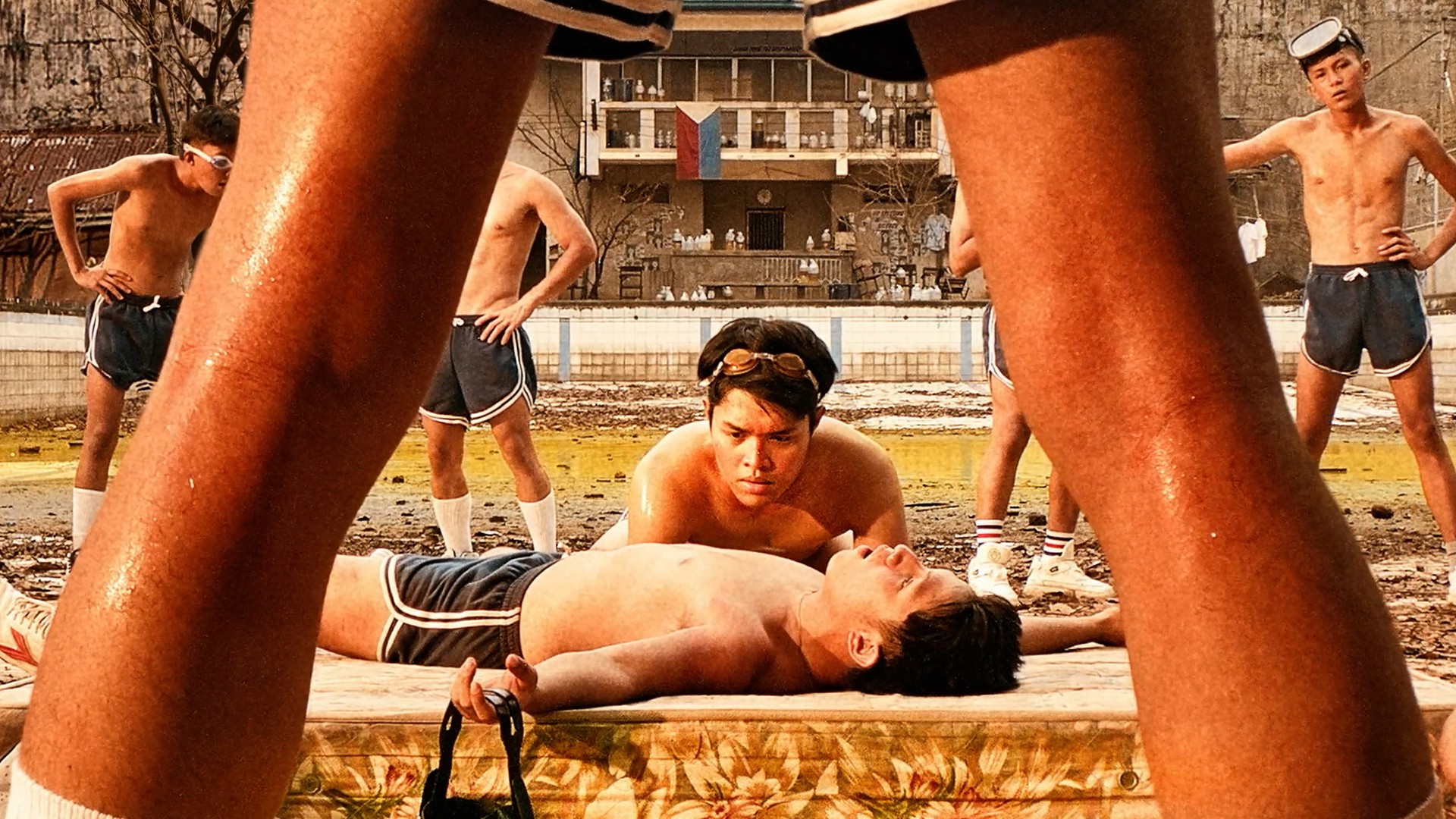 a dying boy is framed by another boy's legs.
