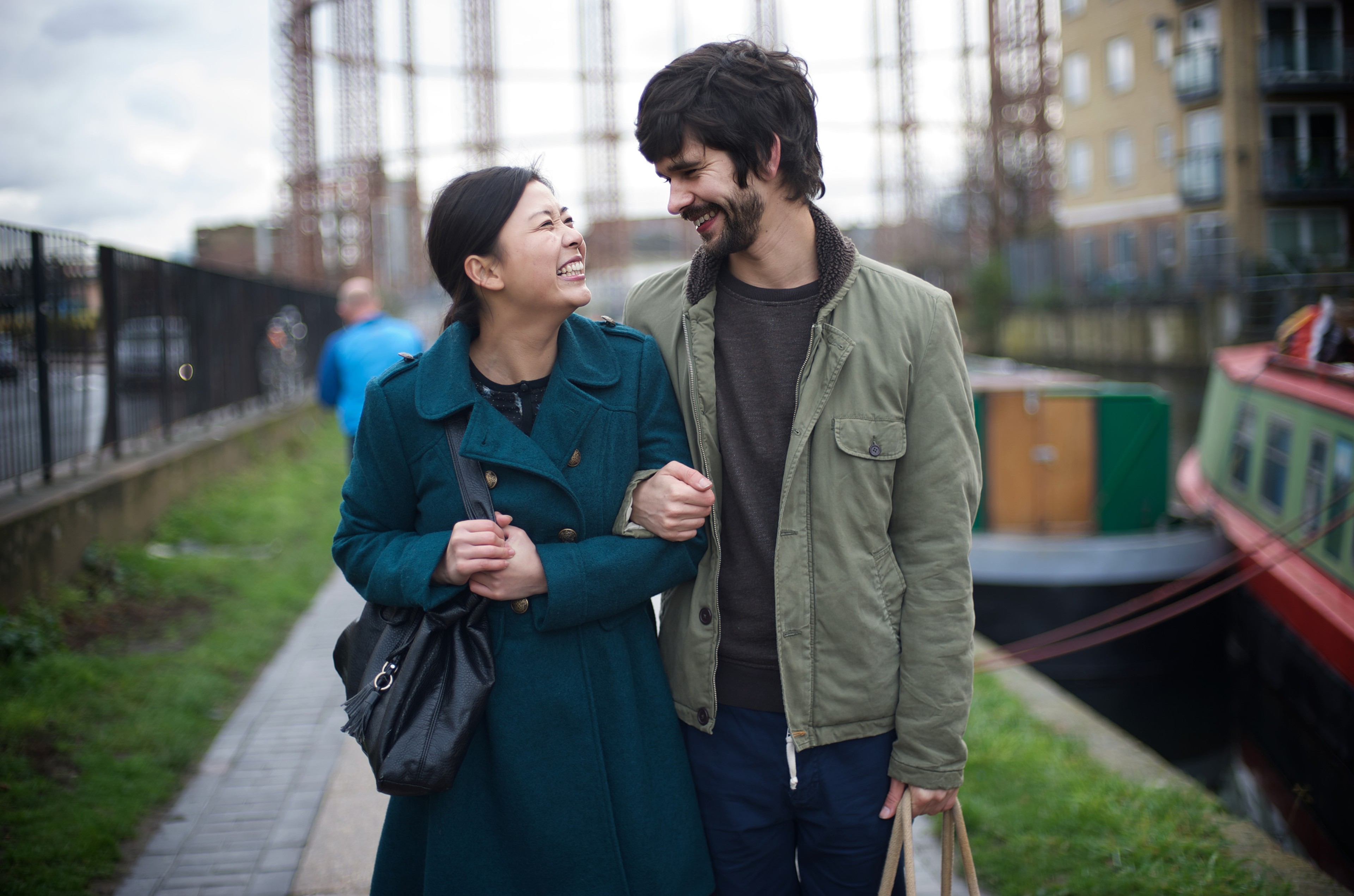 A man and a woman linking arms and smiling at each other.