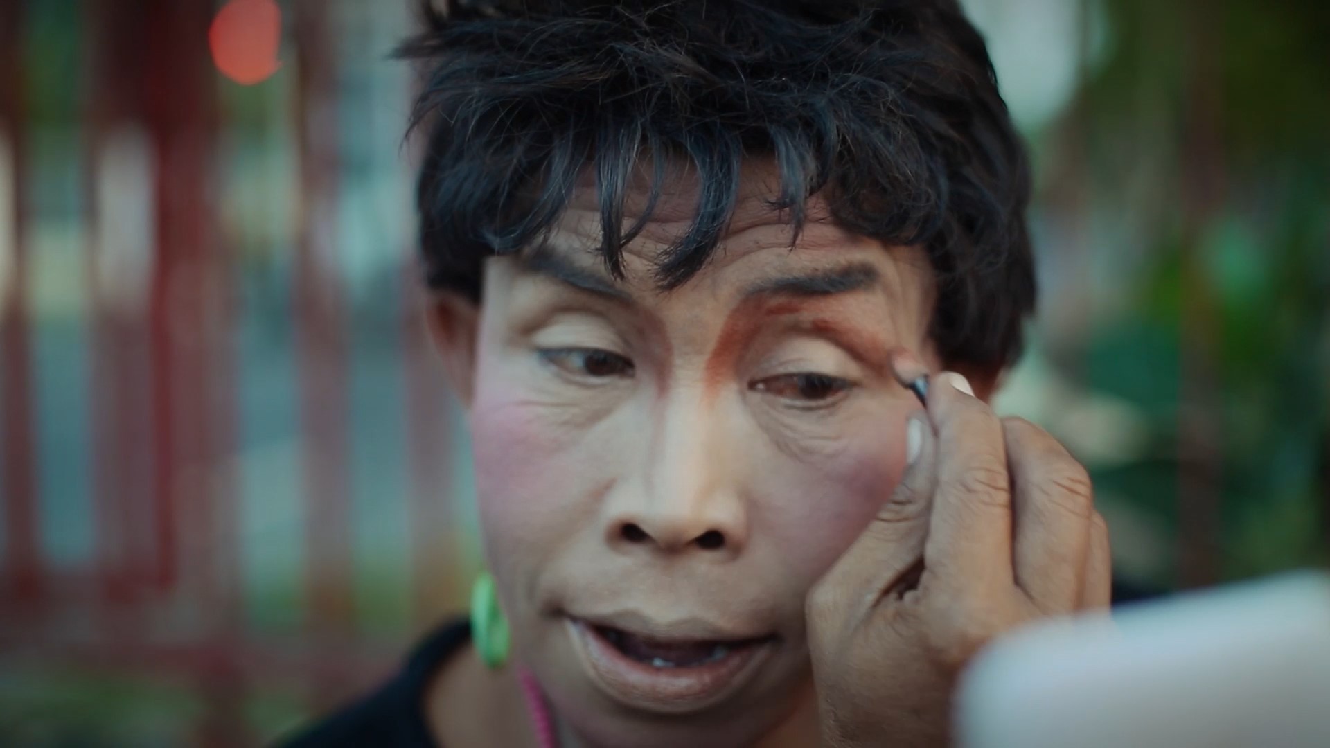 A person applying eye makeup while looking into a mirror.