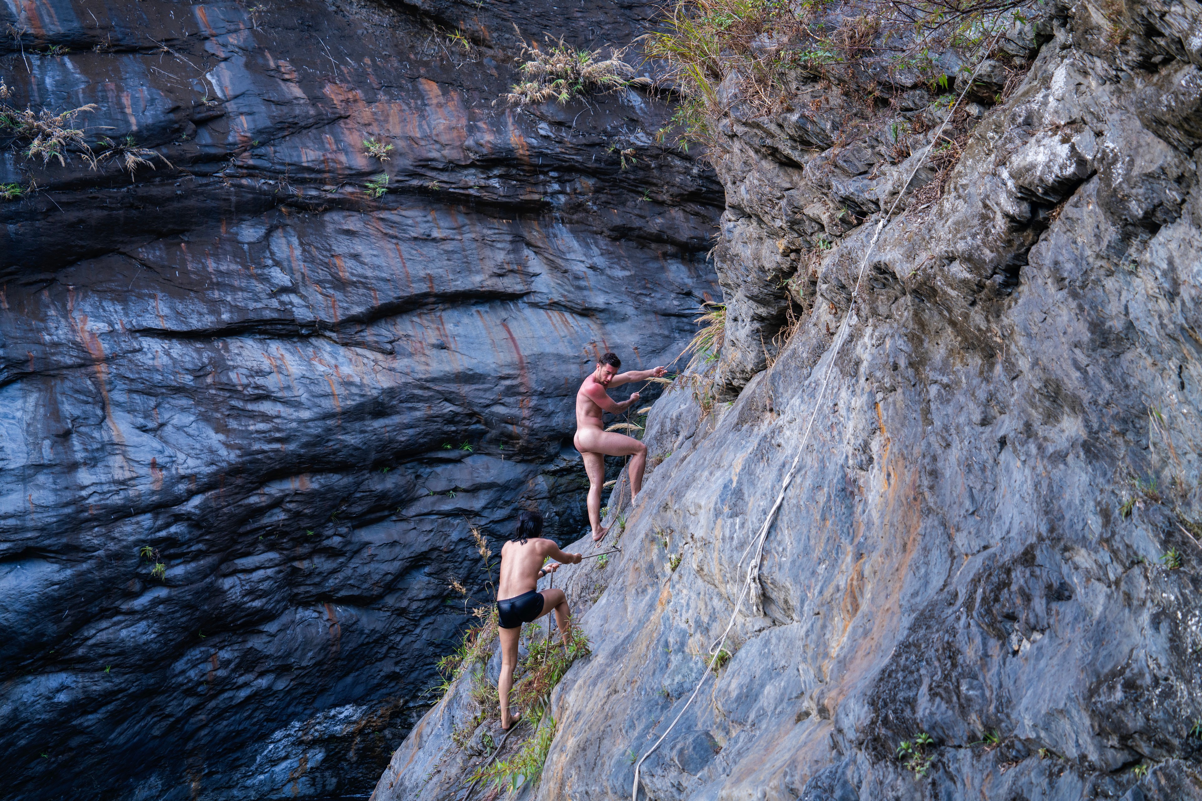 Two men climb a rock face.