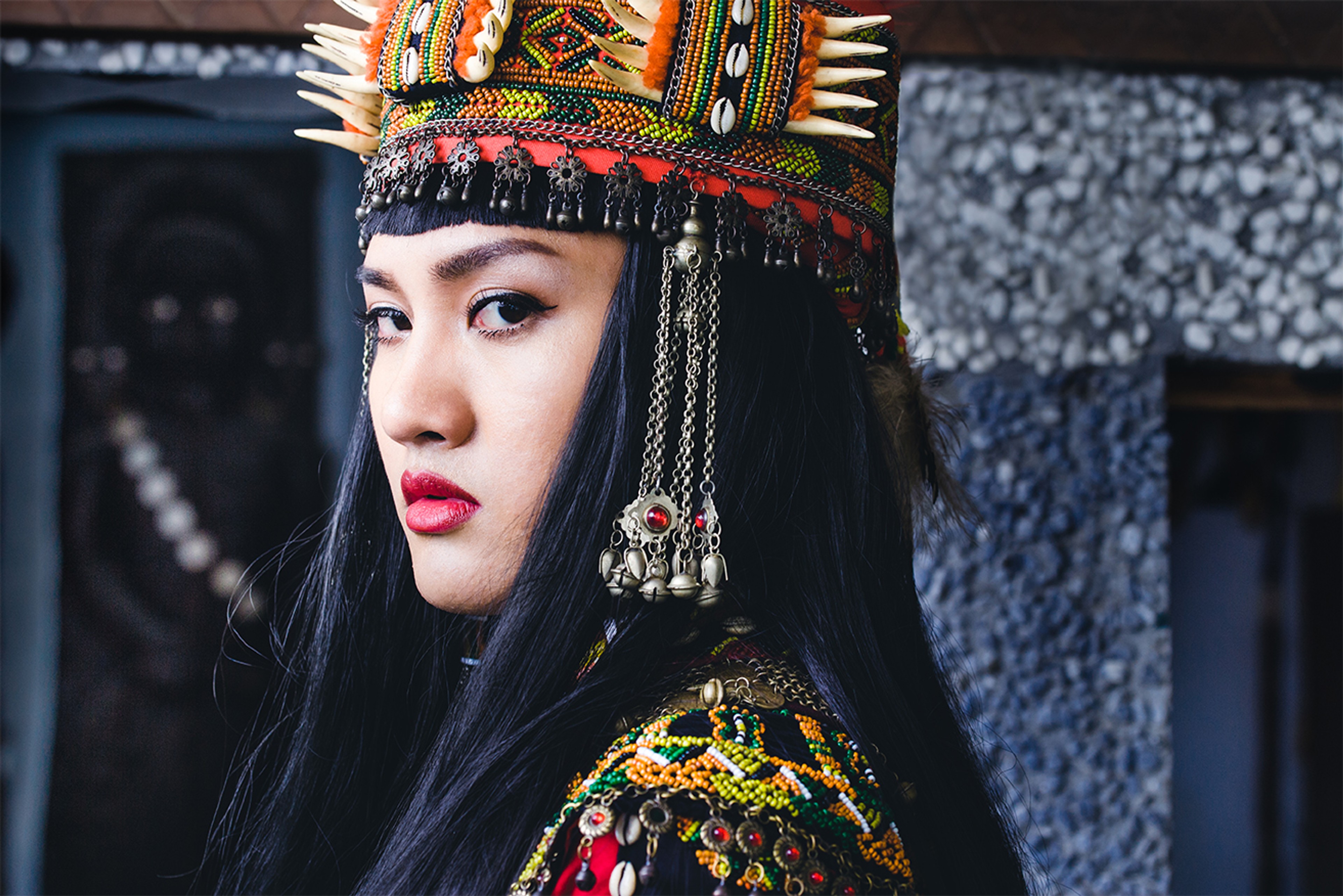 A person with long black hair and a colourful headdress.