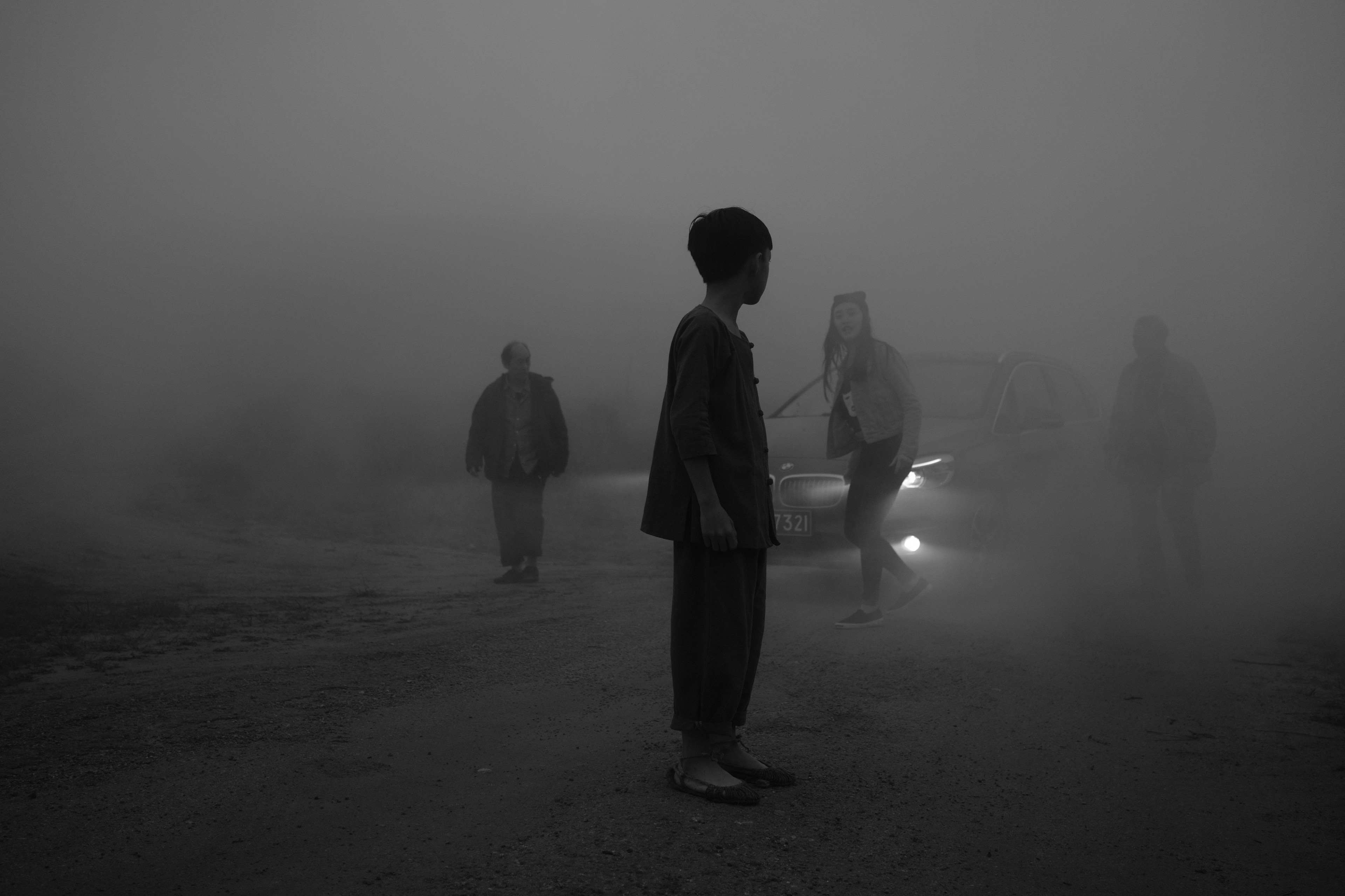 Four figures stand in the fog.