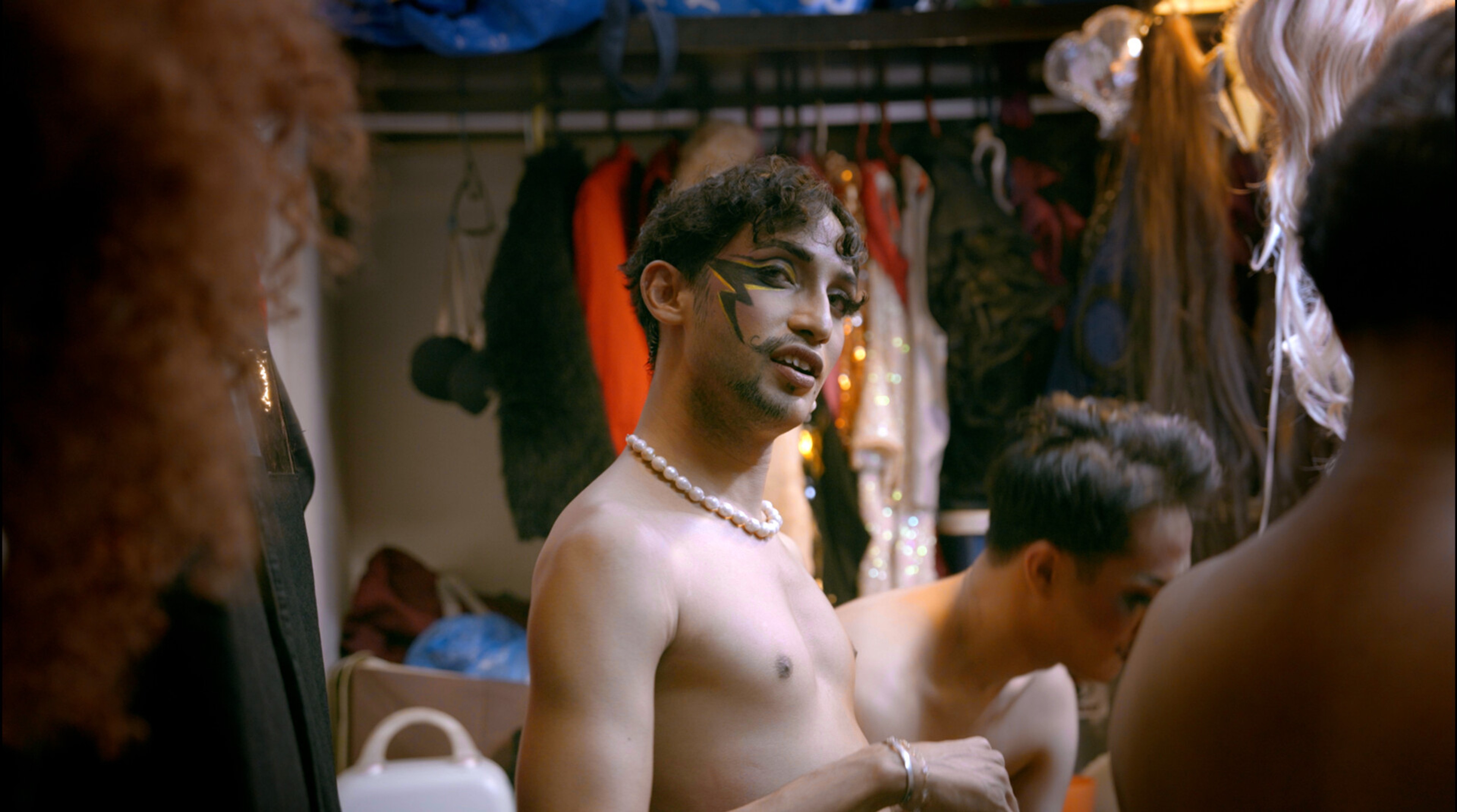 A person with black eye-makeup in a dressing room.