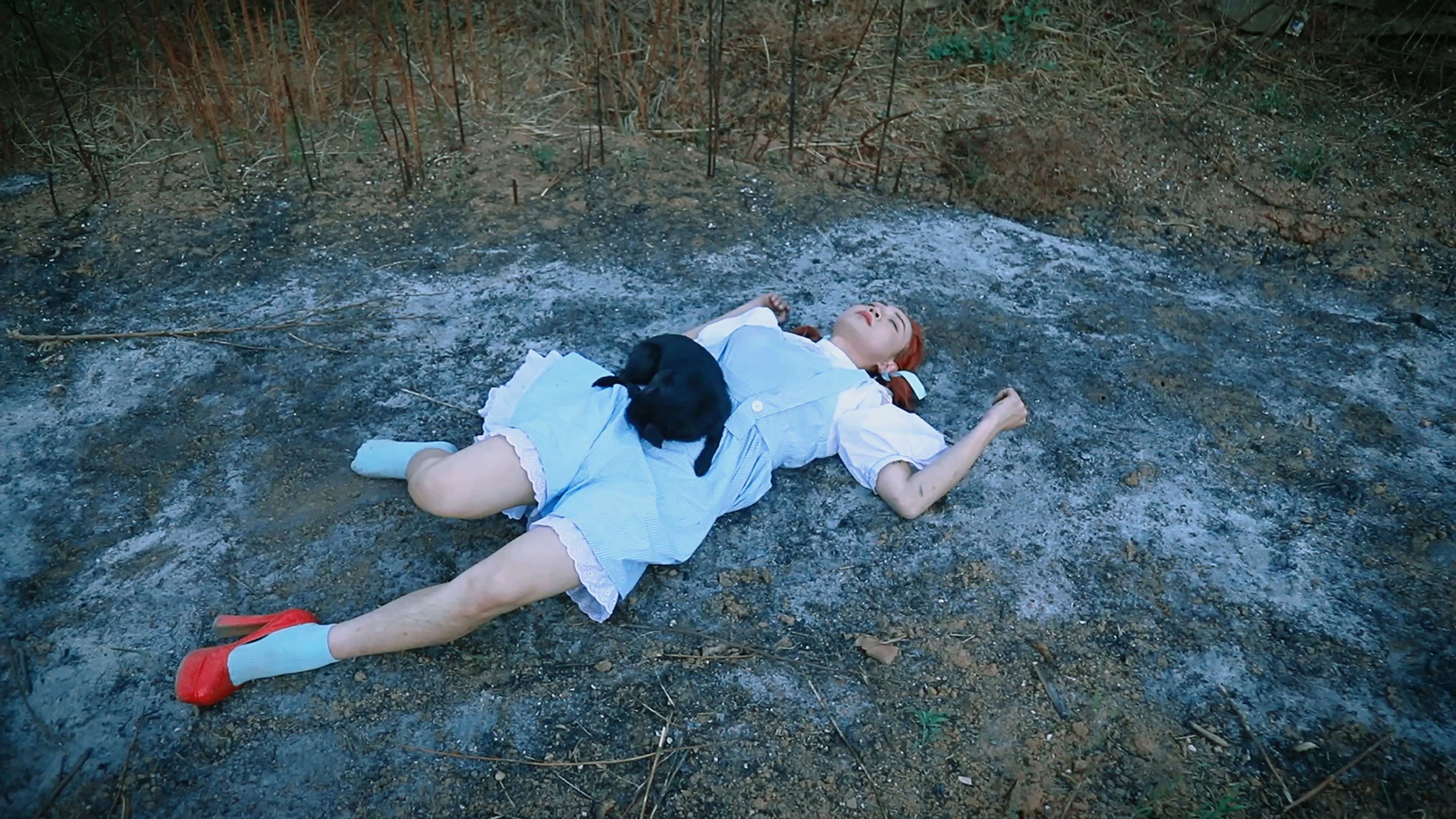 A person in a blue dress lying on the ground.