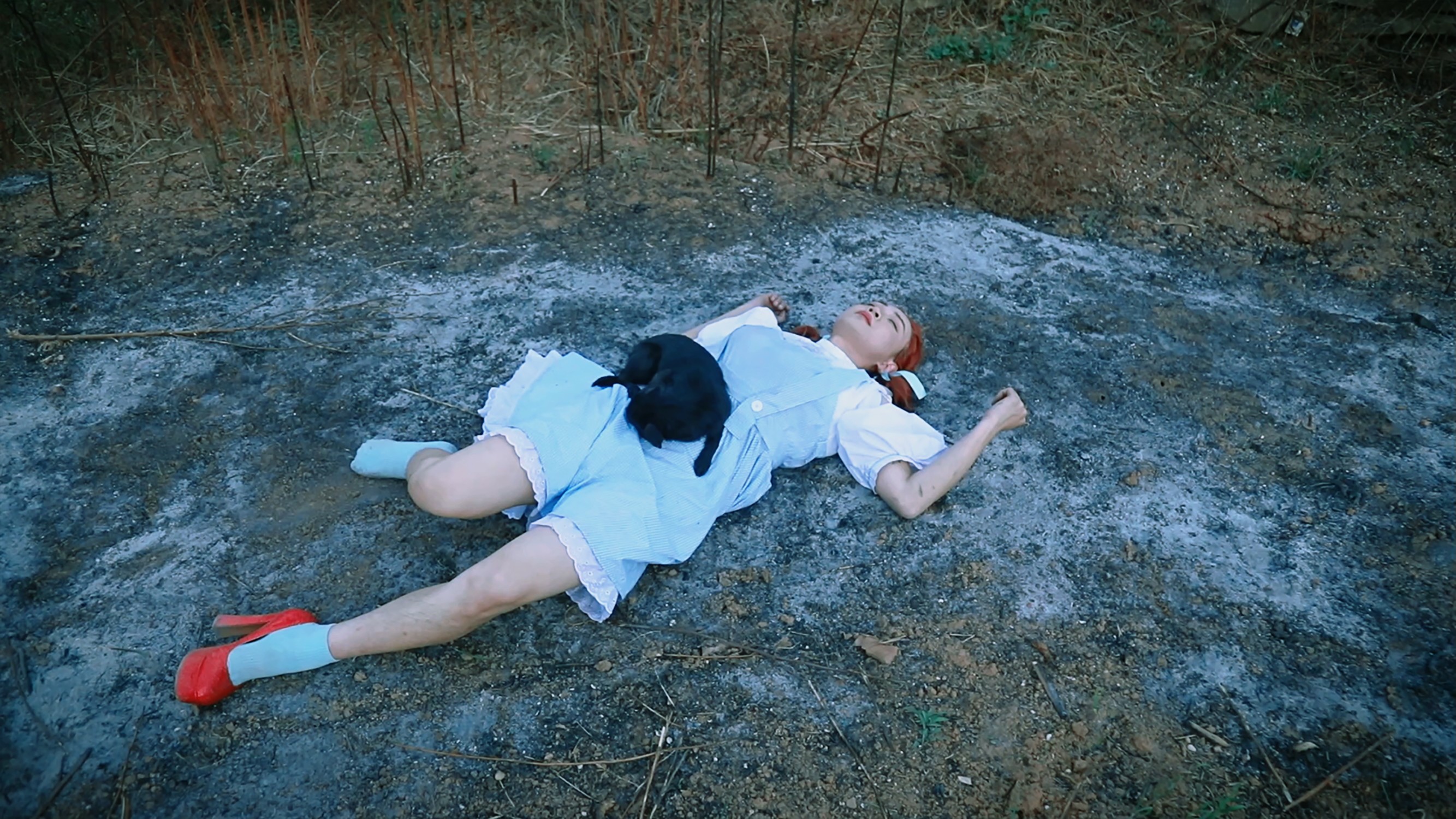 A person in a blue dress lying on the ground.