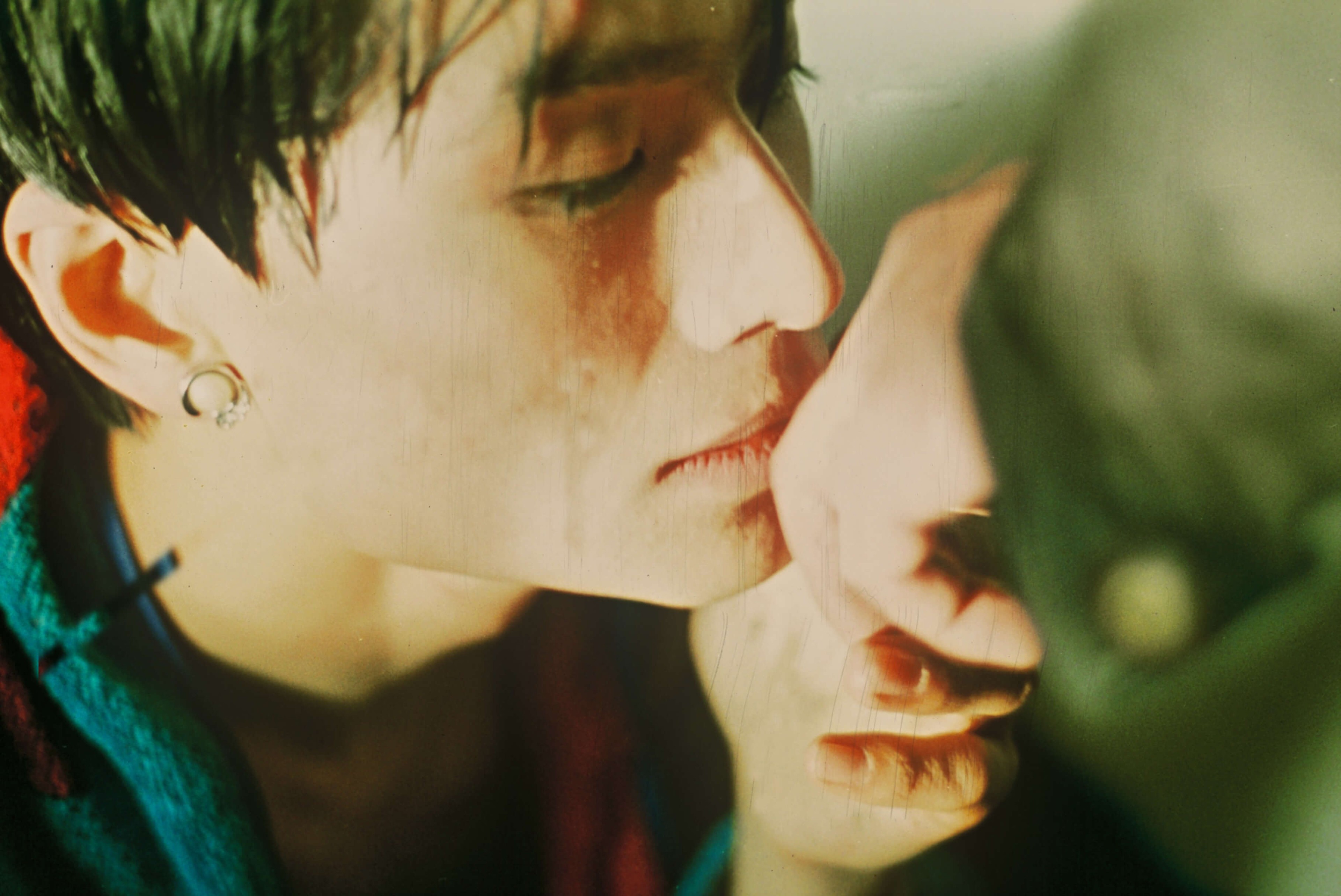 Two people leaning closely together, their faces nearly touching in an intimate close-up.