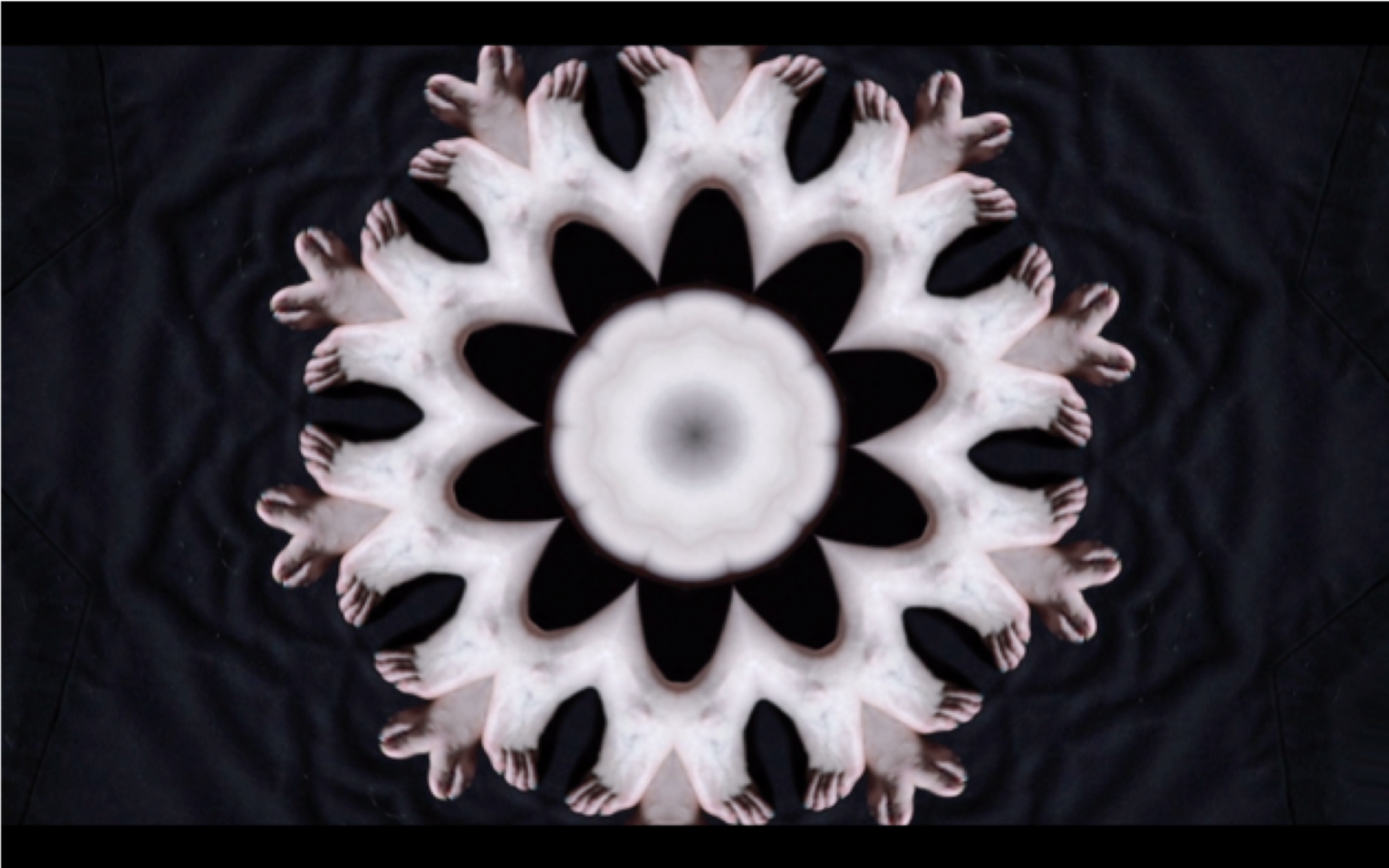 A symmetrical, kaleidoscopic arrangement of human figures forming a flower-like pattern against a dark background.