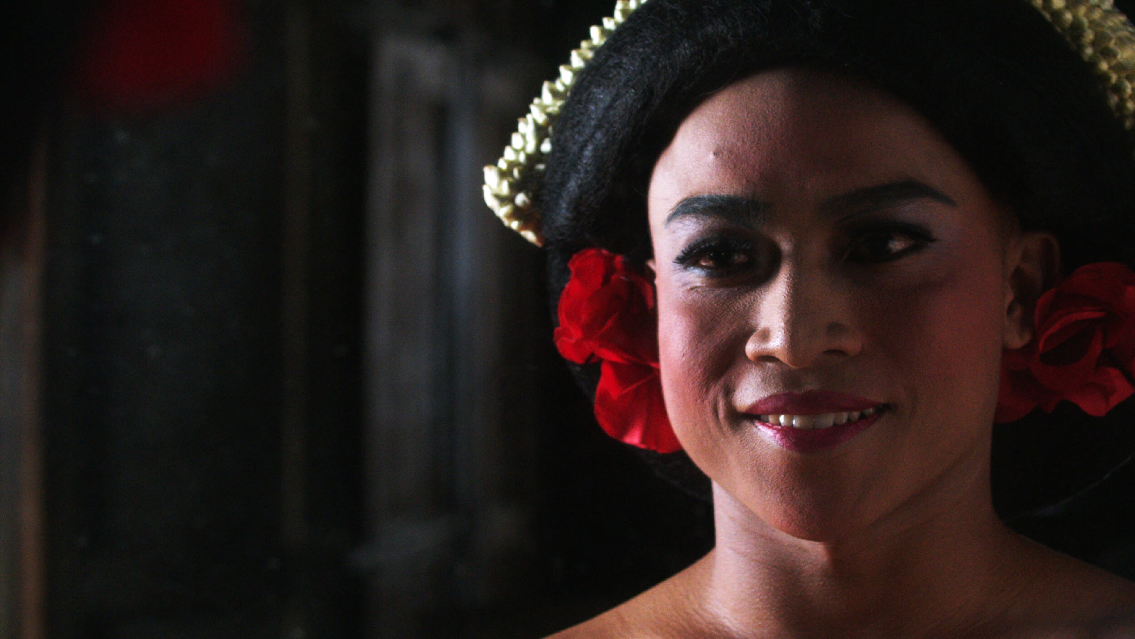 A person's face adorned with makeup and red flowers.