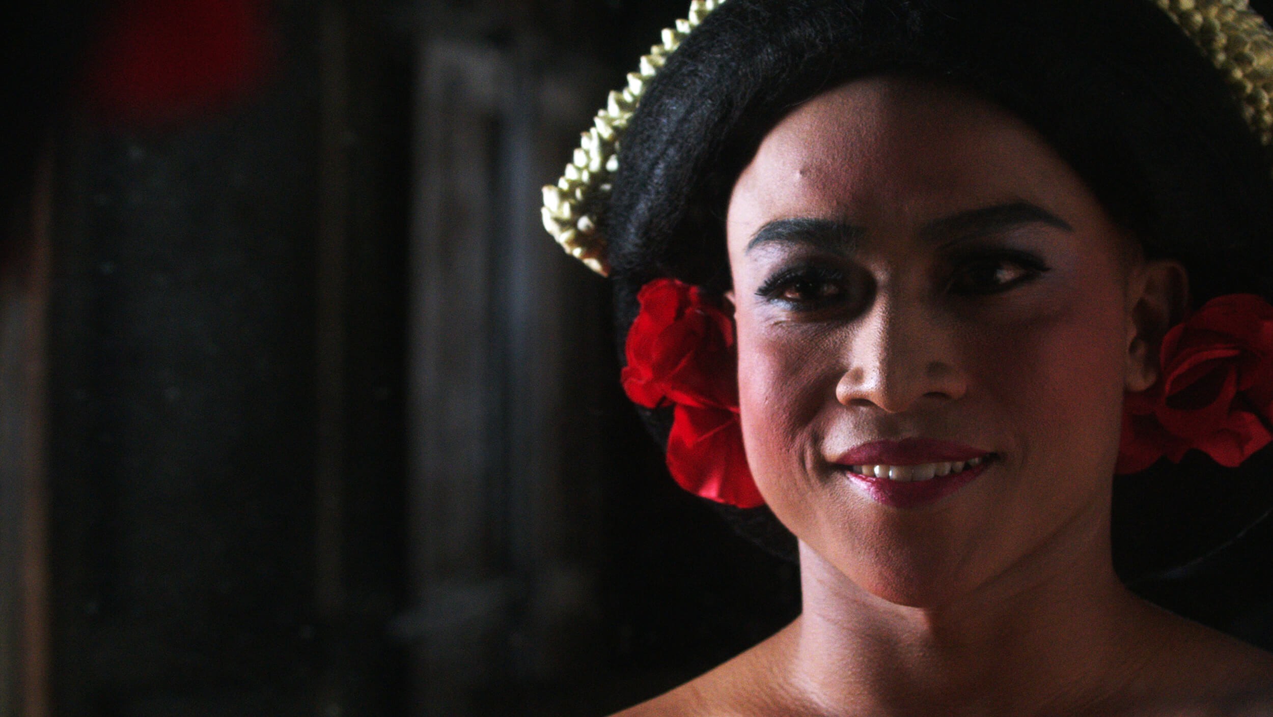 A person's face adorned with makeup and red flowers.