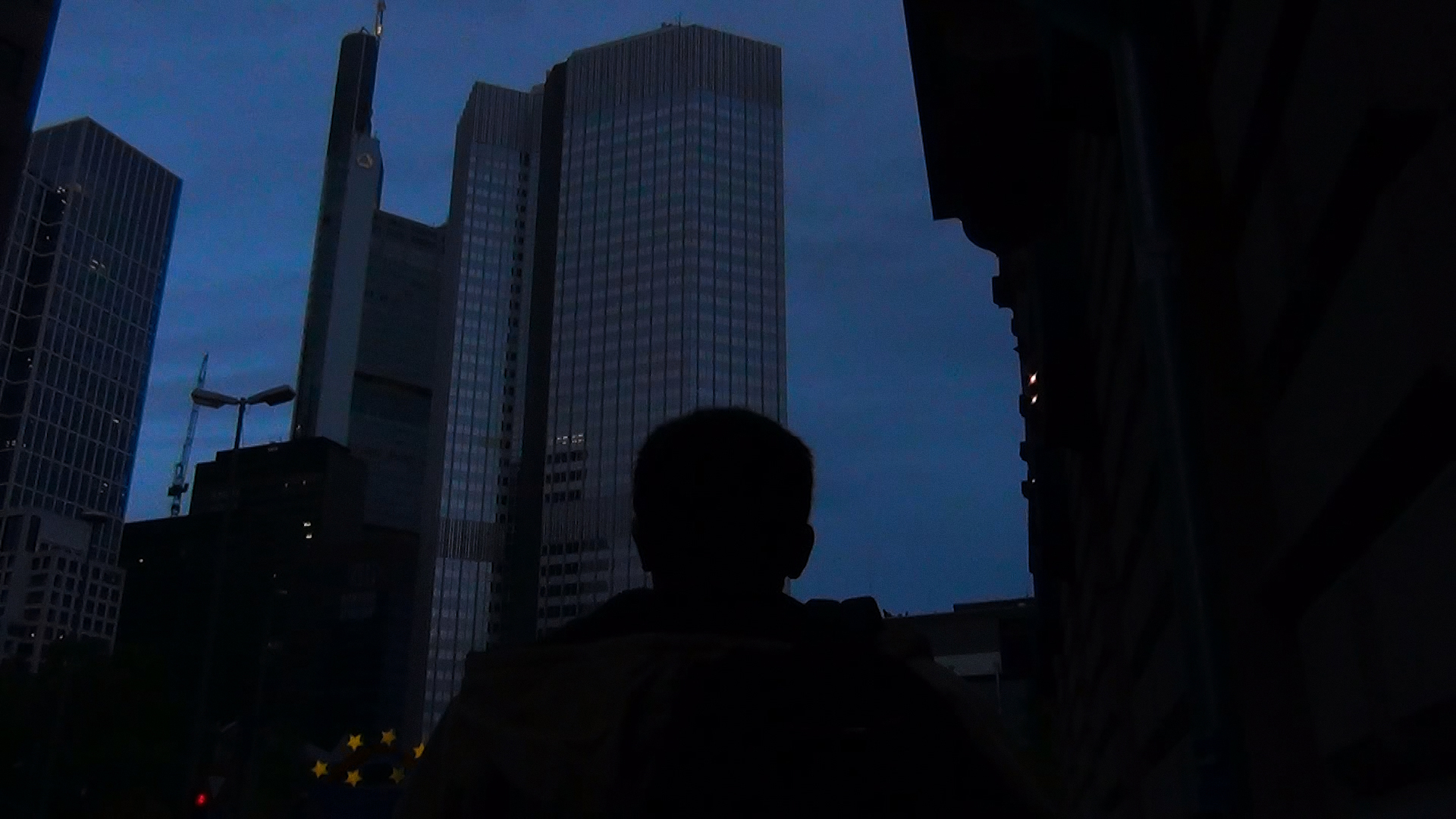 The silhouette of a person against a tall building.
