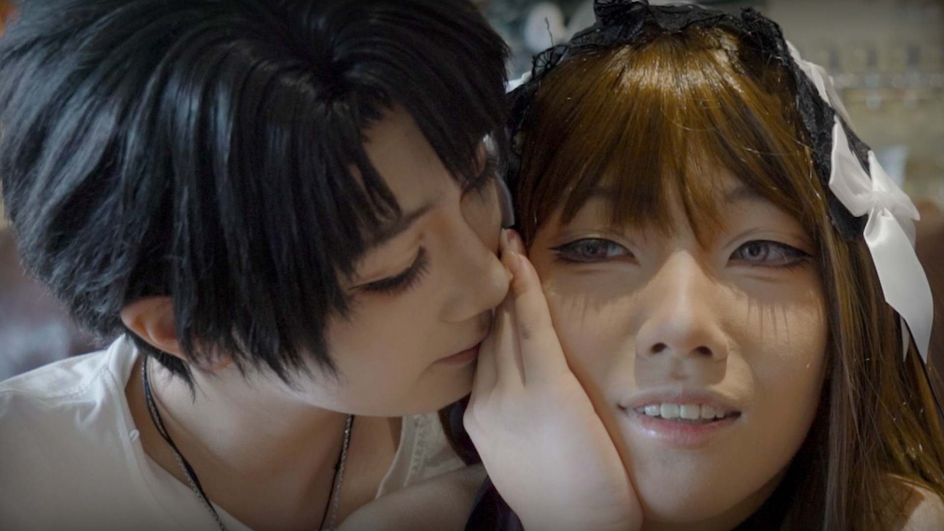 Two people leaning closely together, one gently touching the other’s face.