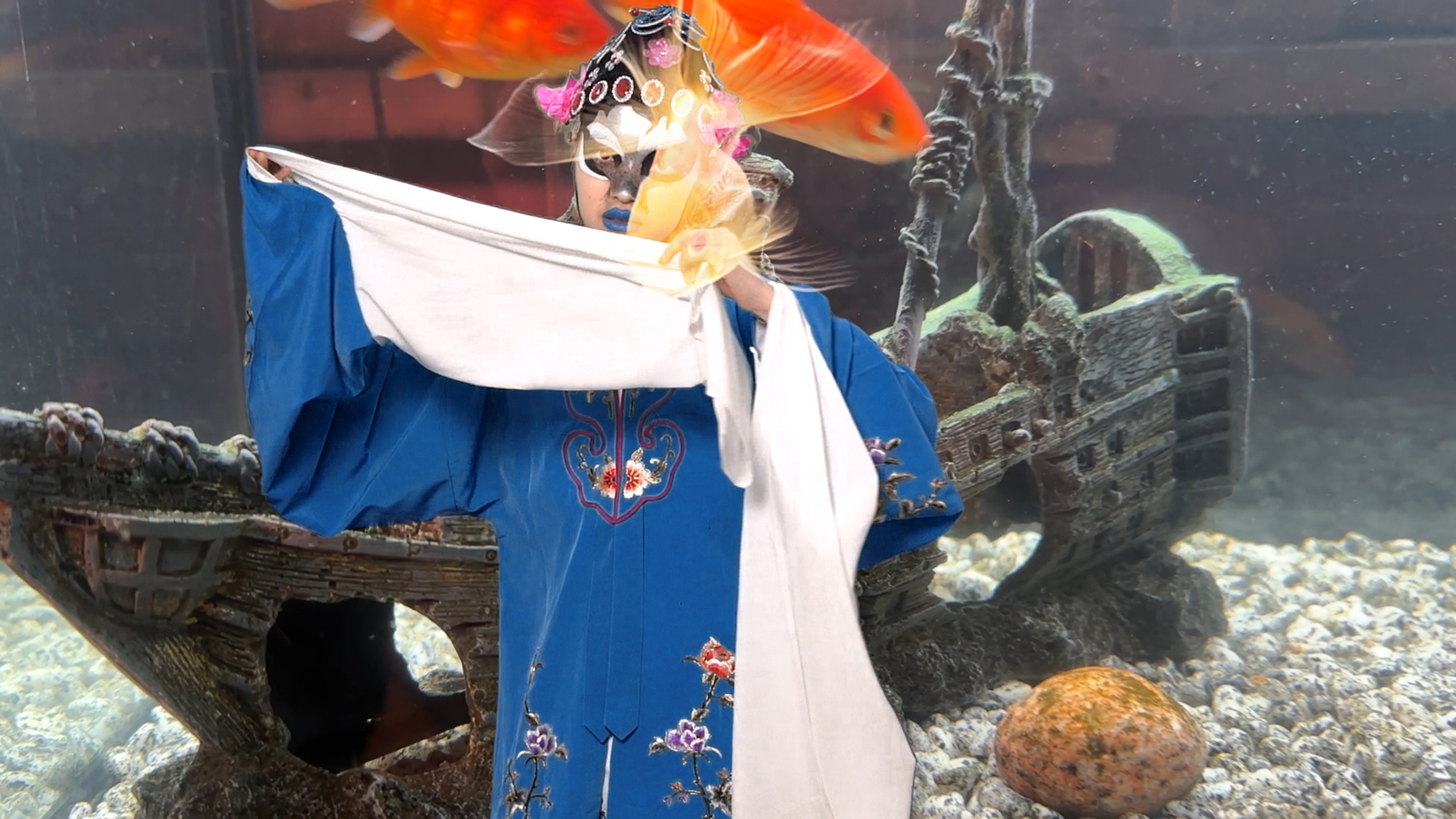 A person wearing long blue robes and drag makeup.