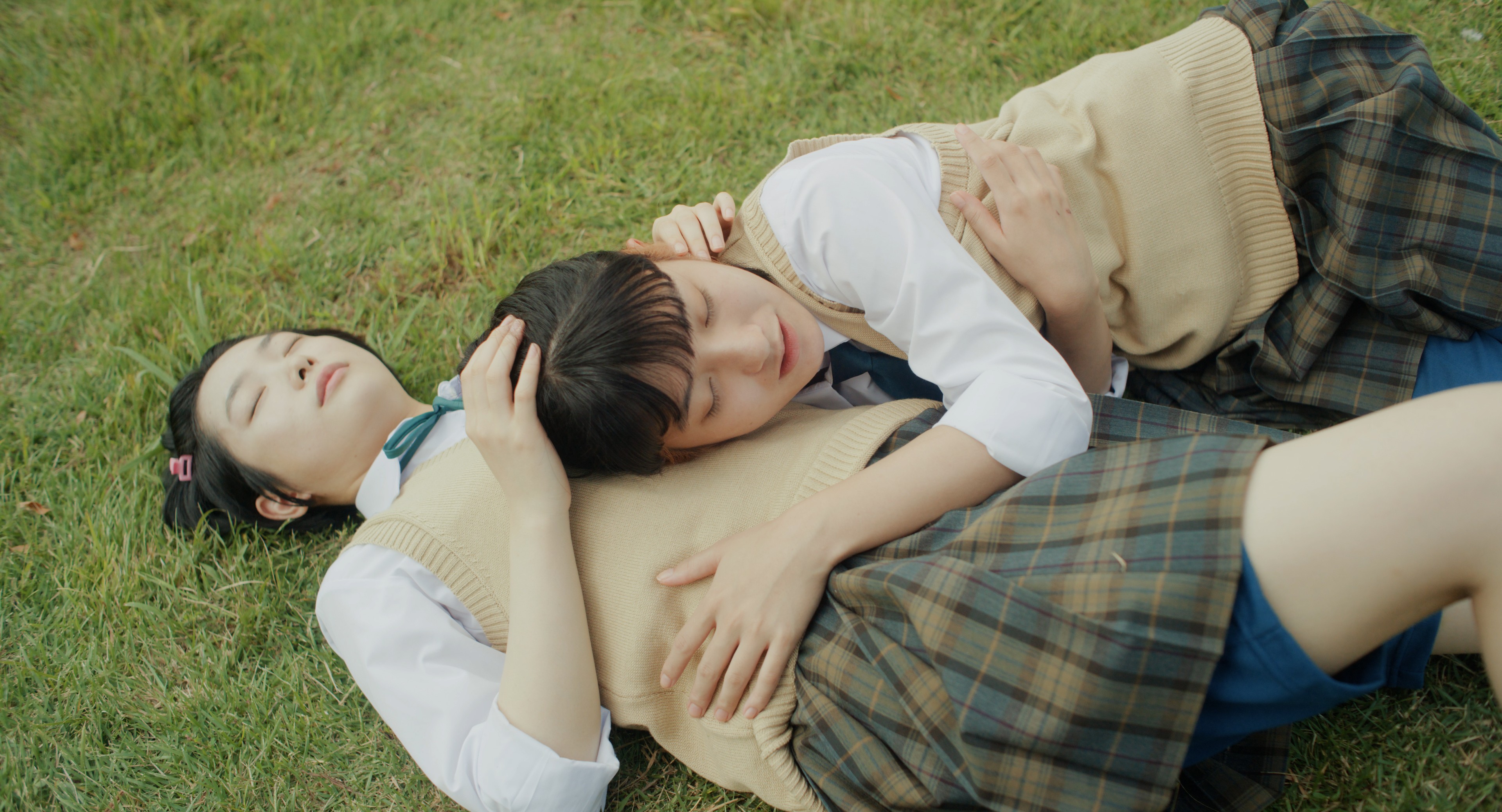 Two girls wearing school uniform embrace.