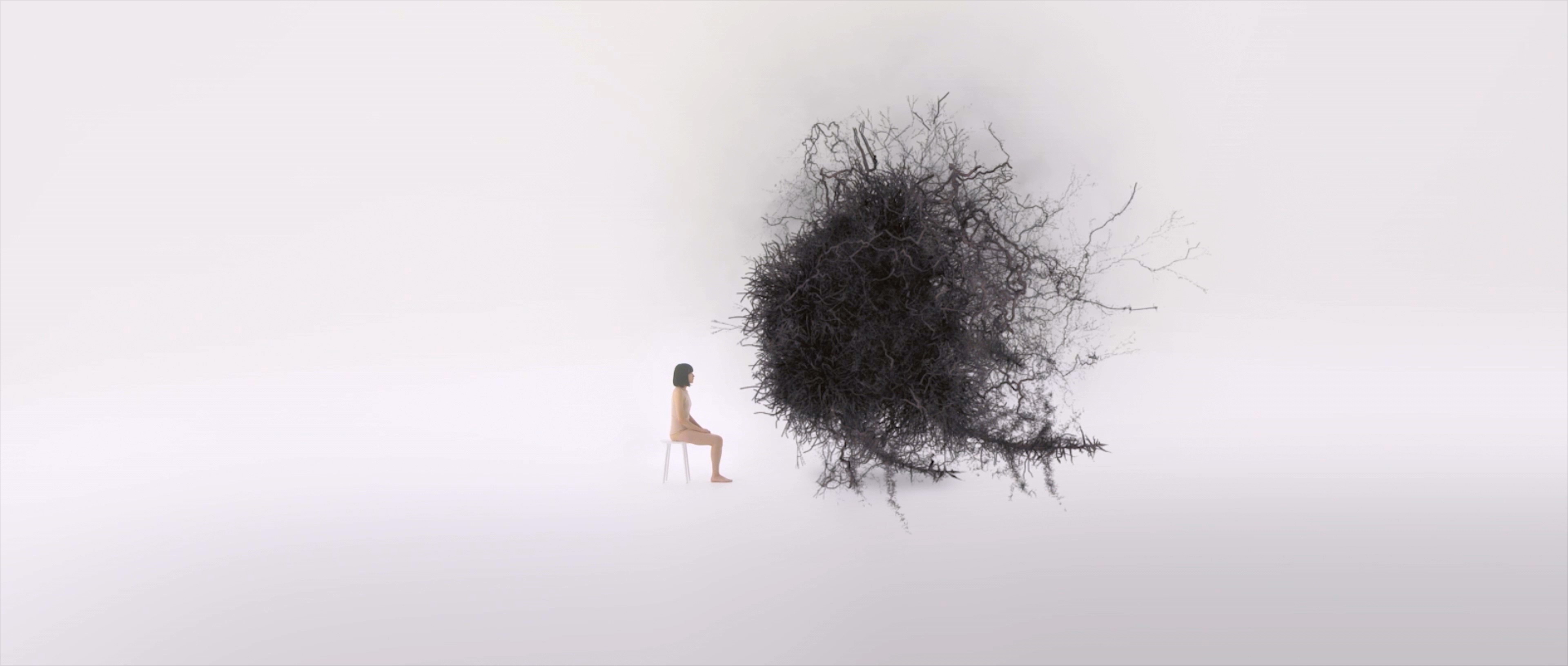A woman sits observing a giant black ball.