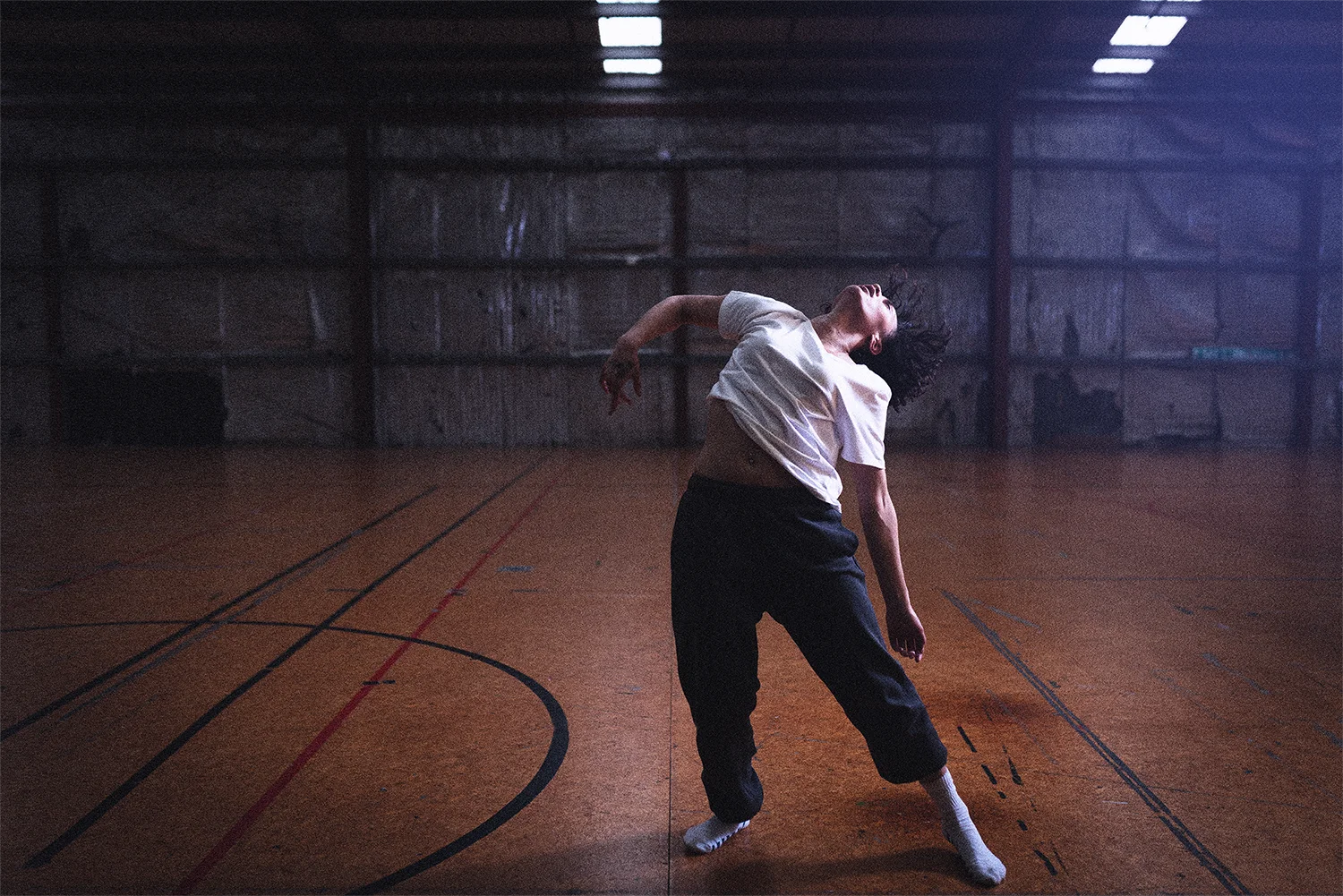 A young woman dances in an empty gymnasium 