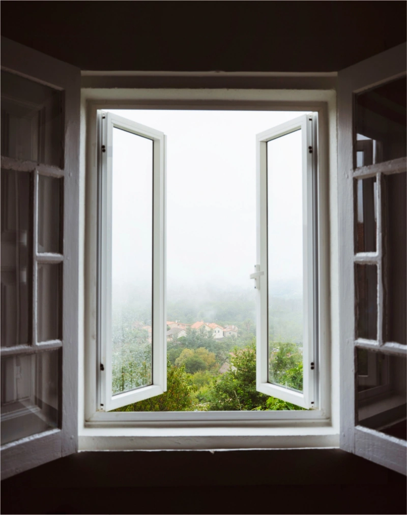 An open window looking out at the countryside on a foggy day