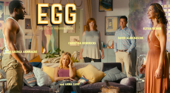 Five people in a room having a conversation, with the EGG title and cast name superimposed over the image