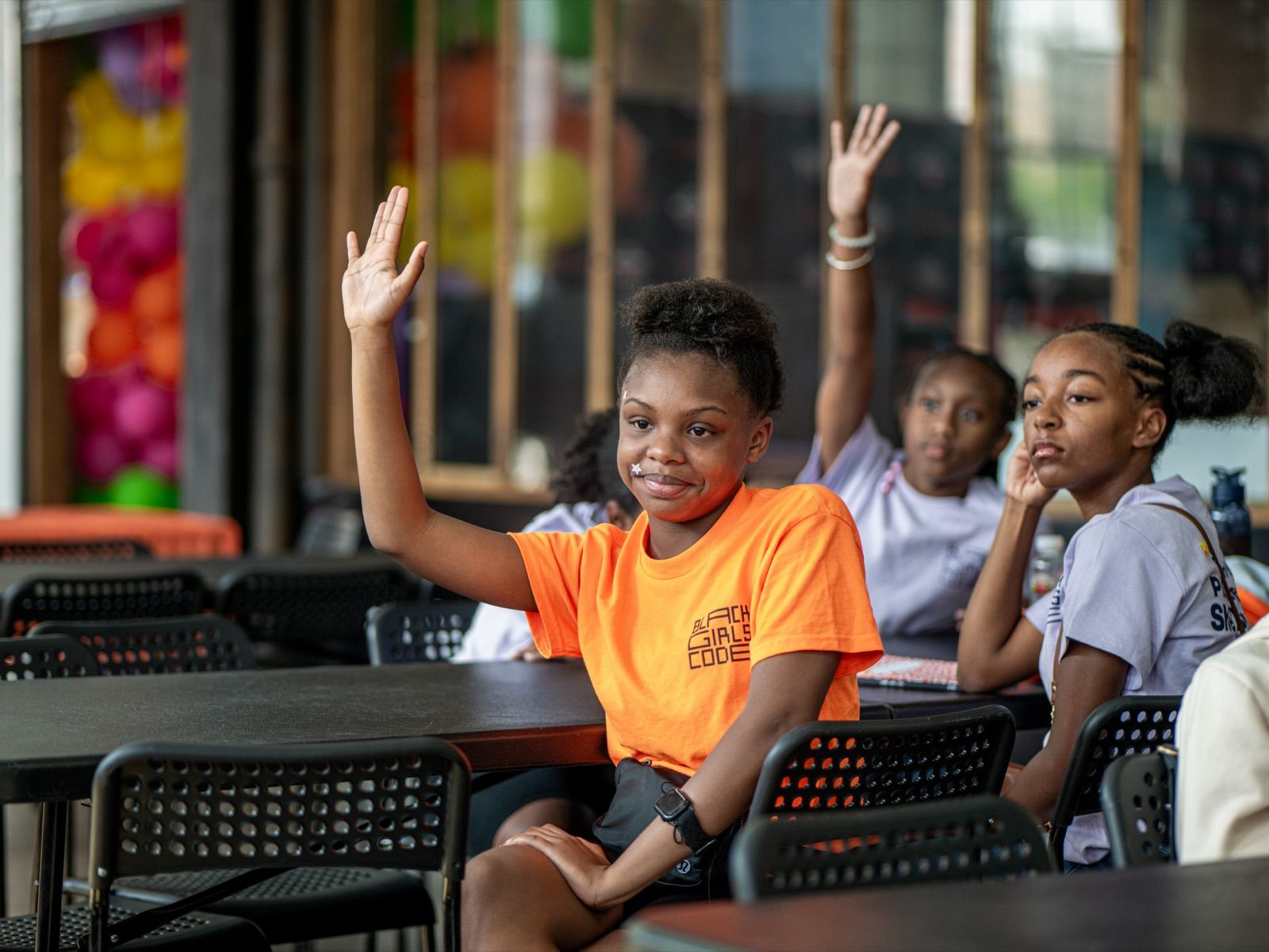 Amina, 12, raising her hand in an orange camp shirt