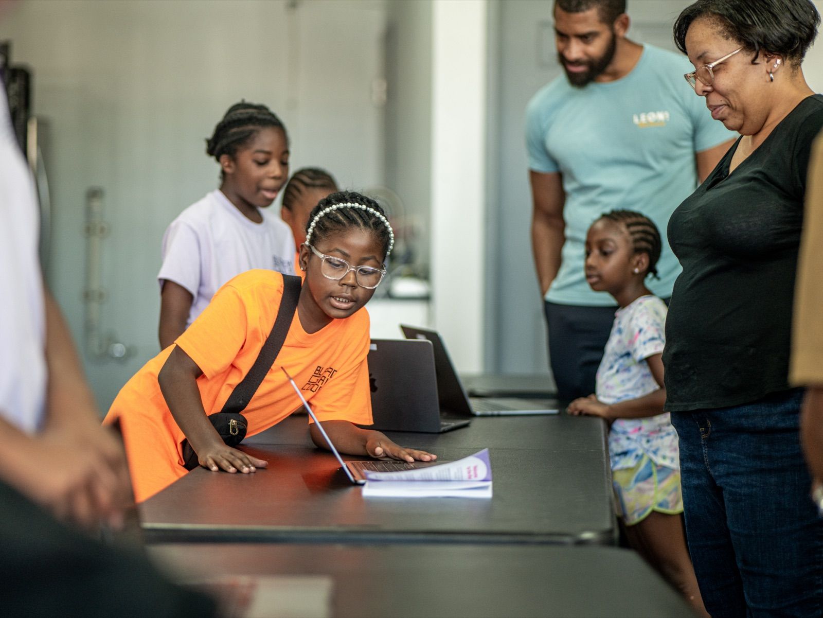 Gabby, 9, leaning over a laptop at camp