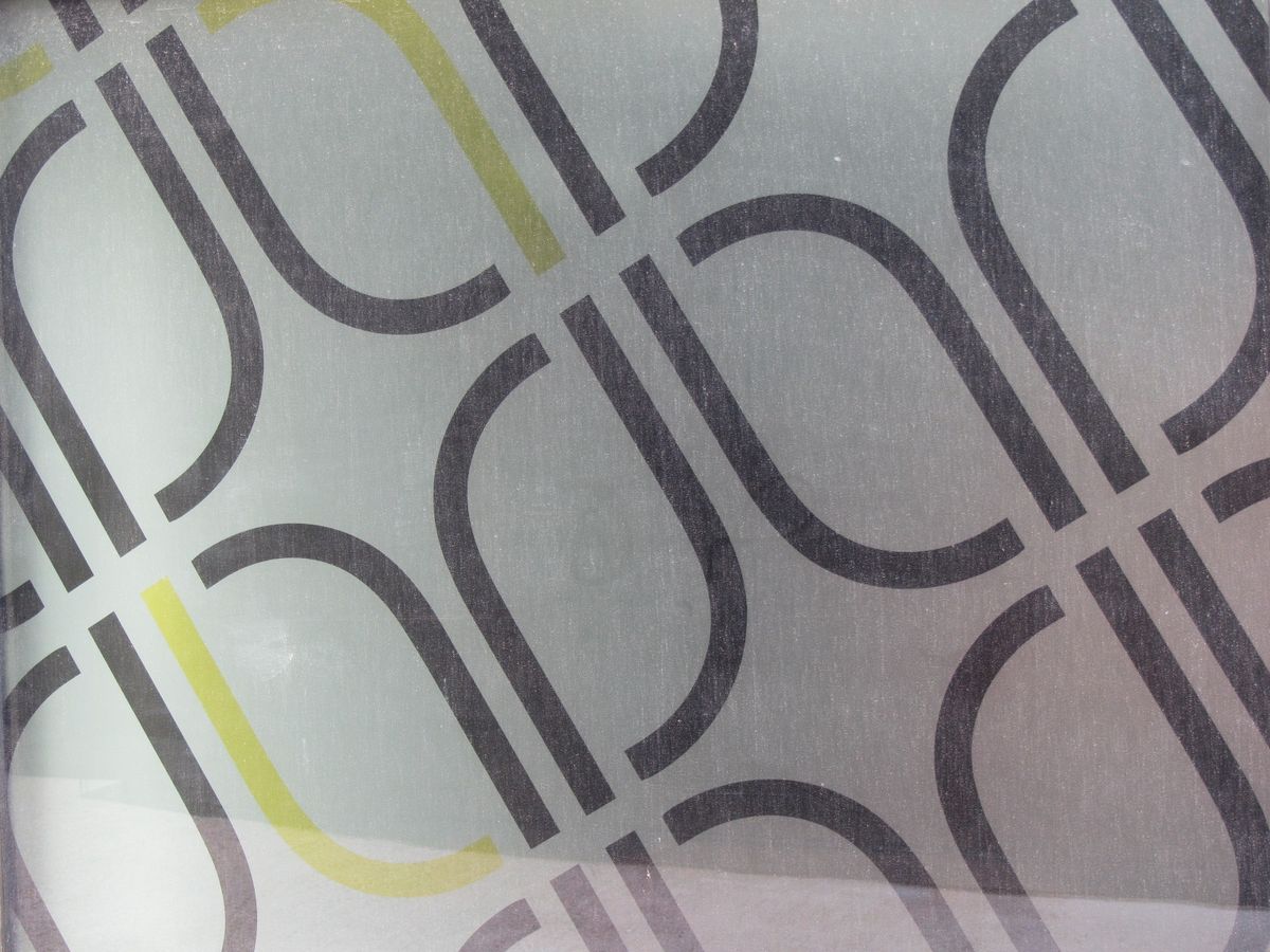 Close-up of the frosted window film: overlapping grey loops with a fine yellow line running through them