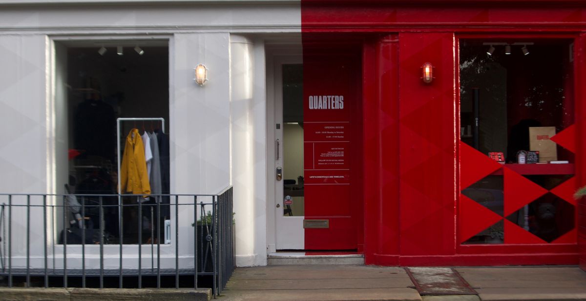 Shopfront with a white window bay showing a jacket and a red bay with the Quarters name and a red-and-black diamond pattern, behind black railings
