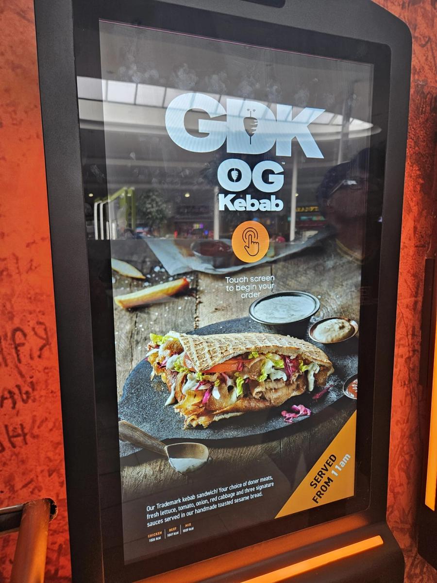 A GDK self-ordering kiosk in store, its screen showing an OG Kebab promotion, photographed in August 2024