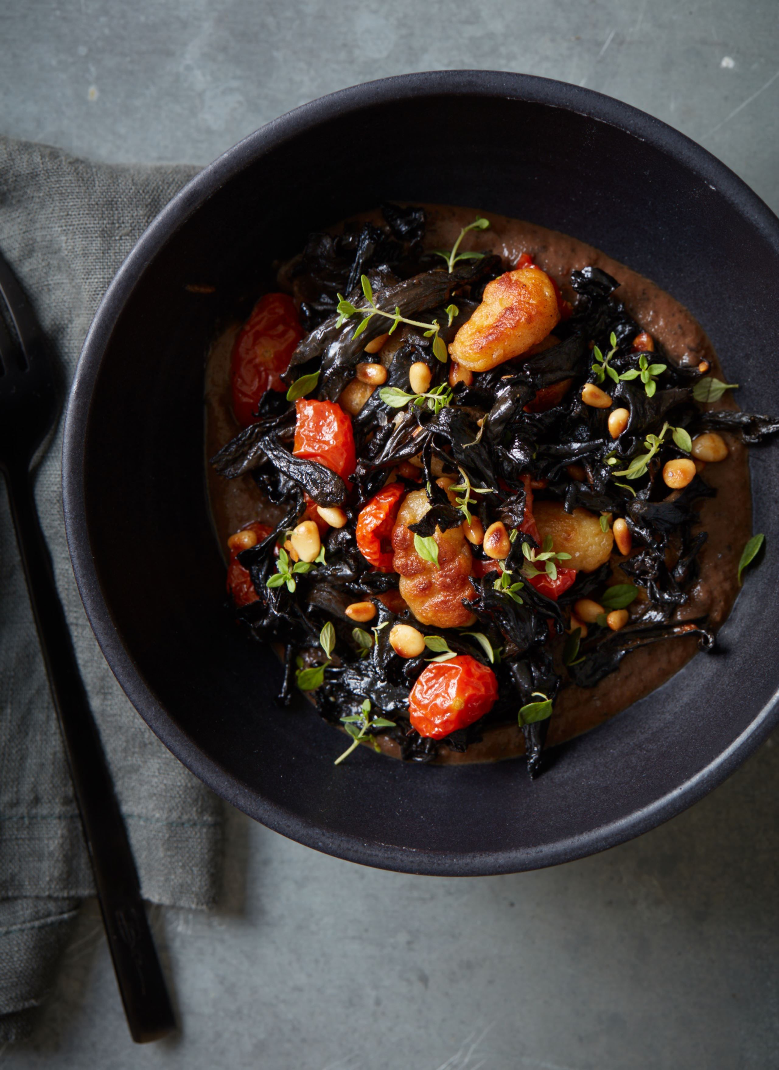 Gnocchi med sort bønnesauce, bagte tomater, timian og trompetsvampe