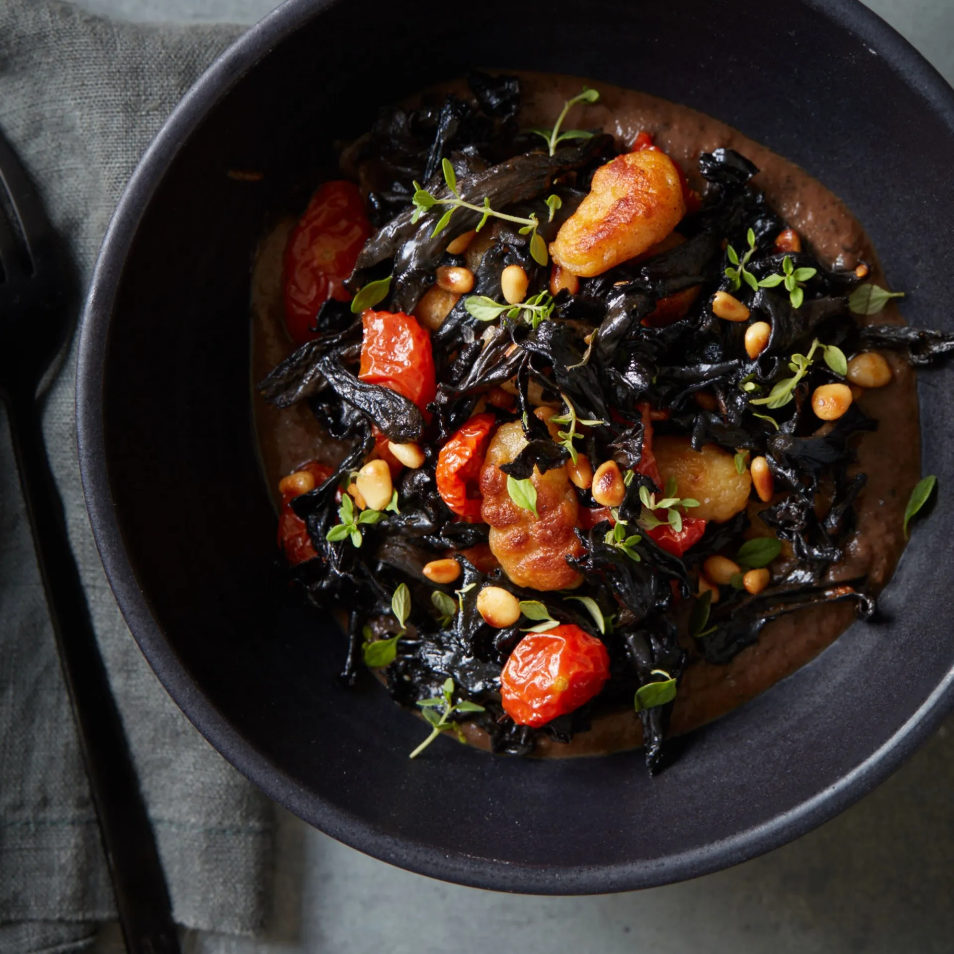 Gnocchi med sort bønnesauce, bagte tomater, timian og trompetsvampe