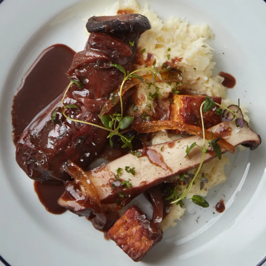 Rødvinsbraiserede kejserhatte med pomerans, sort miso, ristet tempeh og cremet vinterkål