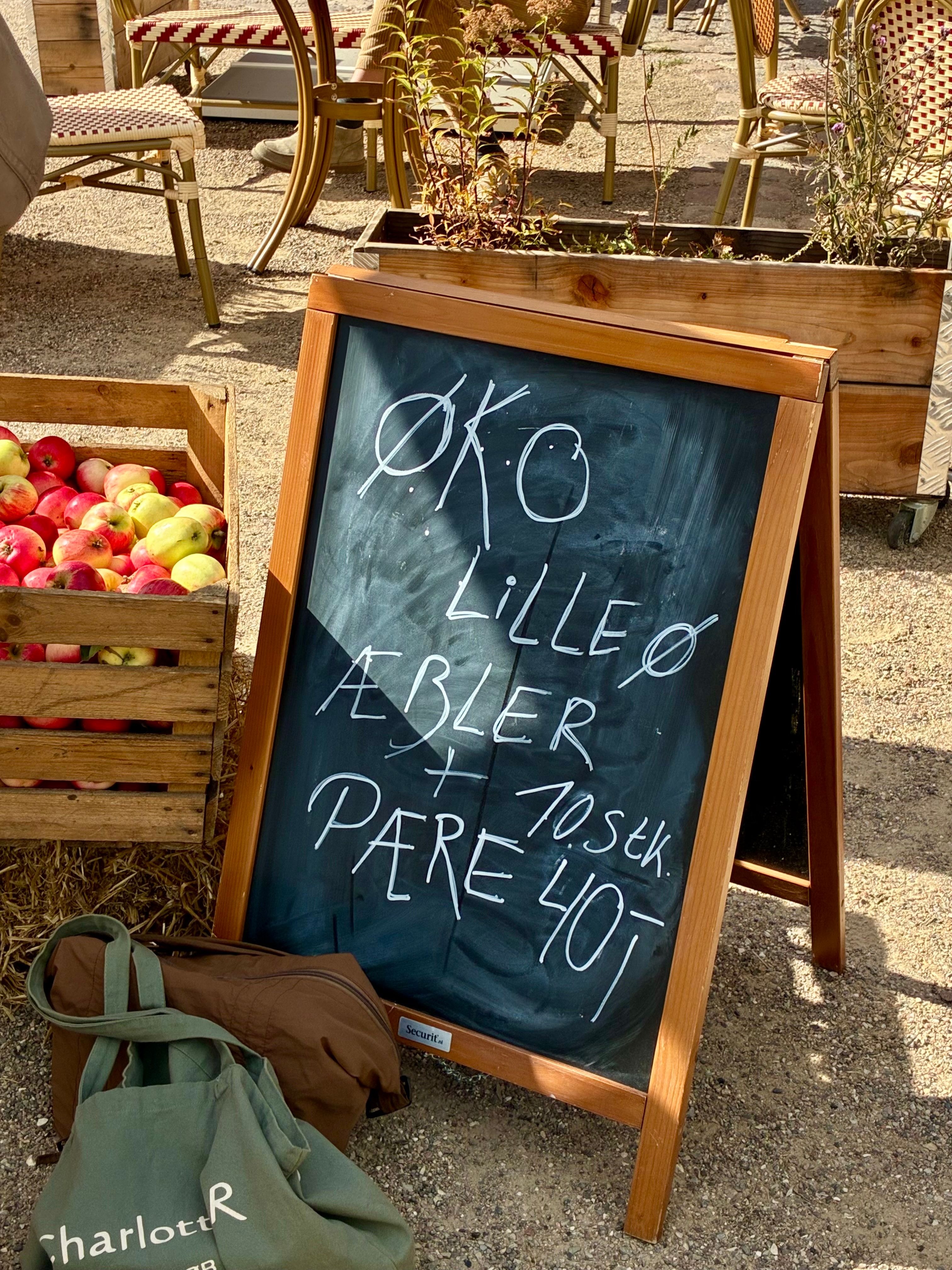 Kasser med økologiske æbler og en kridttavle med æbler og pærer fra Lilleø
