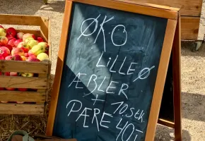 Kasser med økologiske æbler og en kridttavle med æbler og pærer fra Lilleø