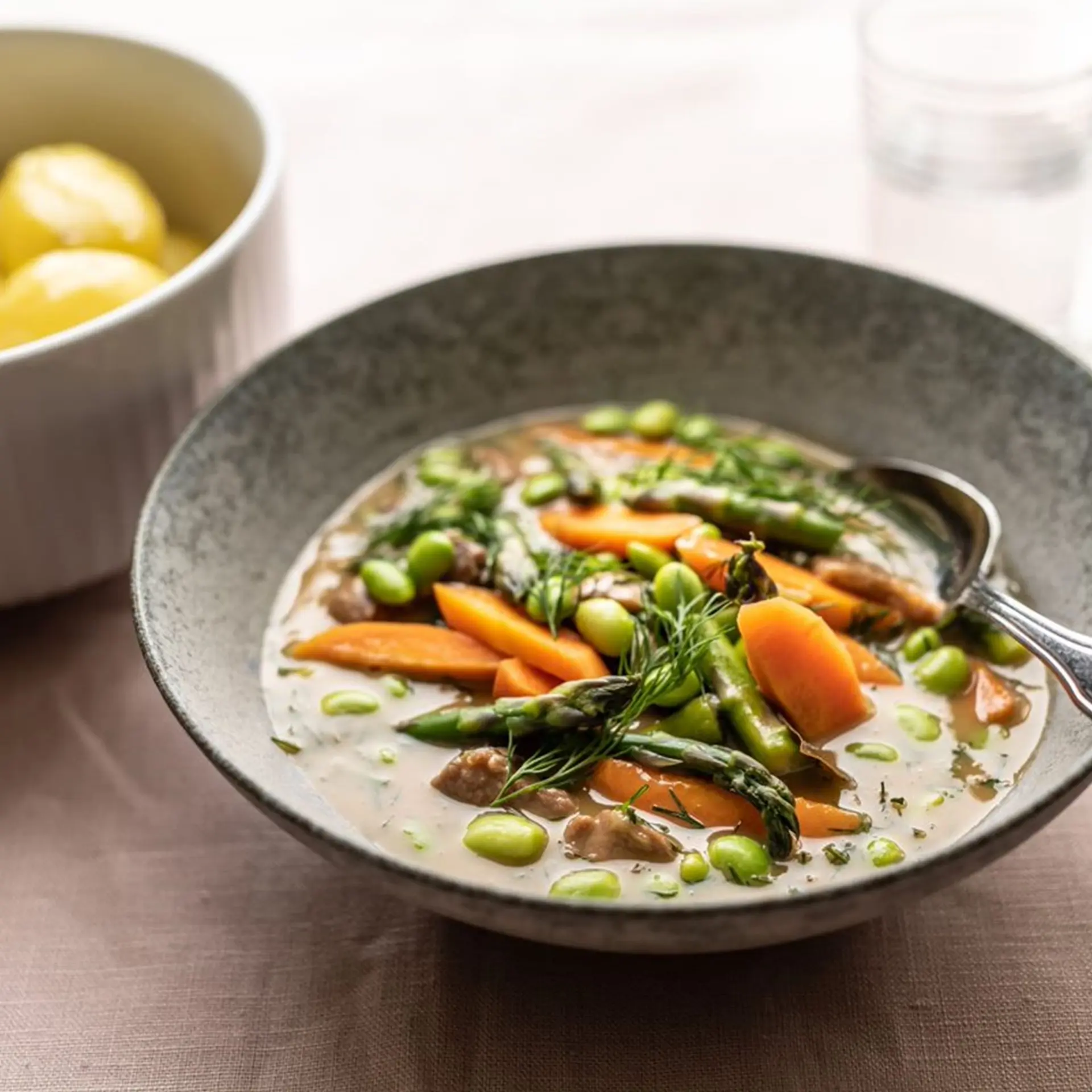Kalkunfrikassé med asparges, gulerødder, edamamebønner og nye kartofler med løvstikke
