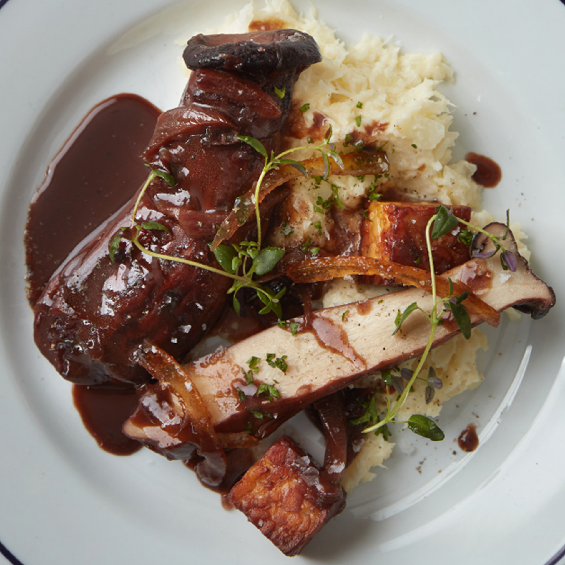 Rødvinsbraiserede kejserhatte med pomerans, sort miso, ristet tempeh og cremet vinterkål