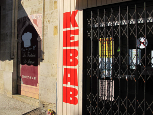 «KEBAB» malt i rødt på hvit plankevegg med vertikal skriveretning ovenfra og ned. Foto: Tristan Etienne.