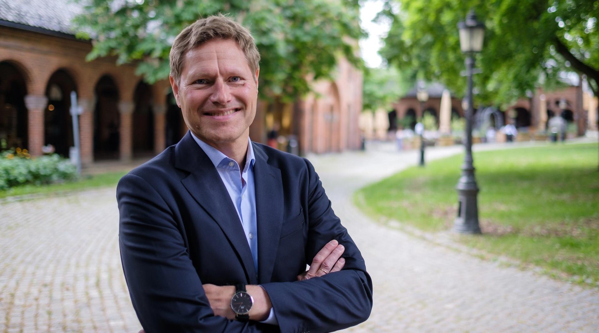 Mann smiler mot kamera med armene i kryss og en utrolig fin klokke på armen