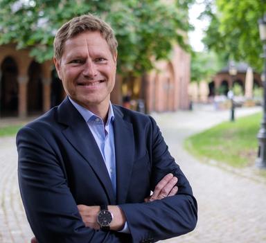 Mann smiler mot kamera med armene i kryss og en utrolig fin klokke på armen