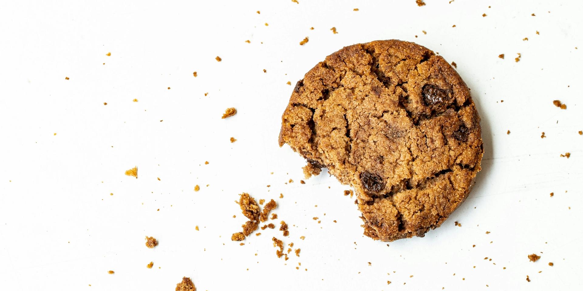 Photo of a cookie with chocolatebites that has been eaten off and cookiecrumbs.