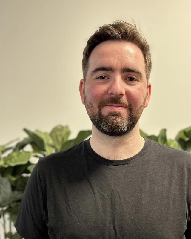 Patrick Vestad ser mot kamera foran grønne planter.