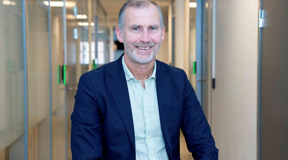 Sigurd Eriksson sitter i en kontorgang og smiler mot kameraet.