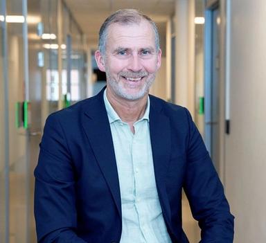 Sigurd Eriksson sitter i en kontorgang og smiler mot kameraet.