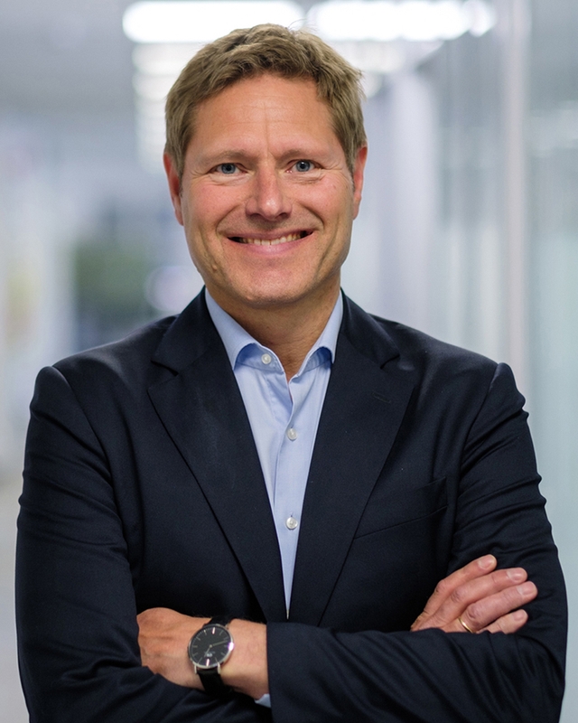 Mann i dress som smiler mot kamera