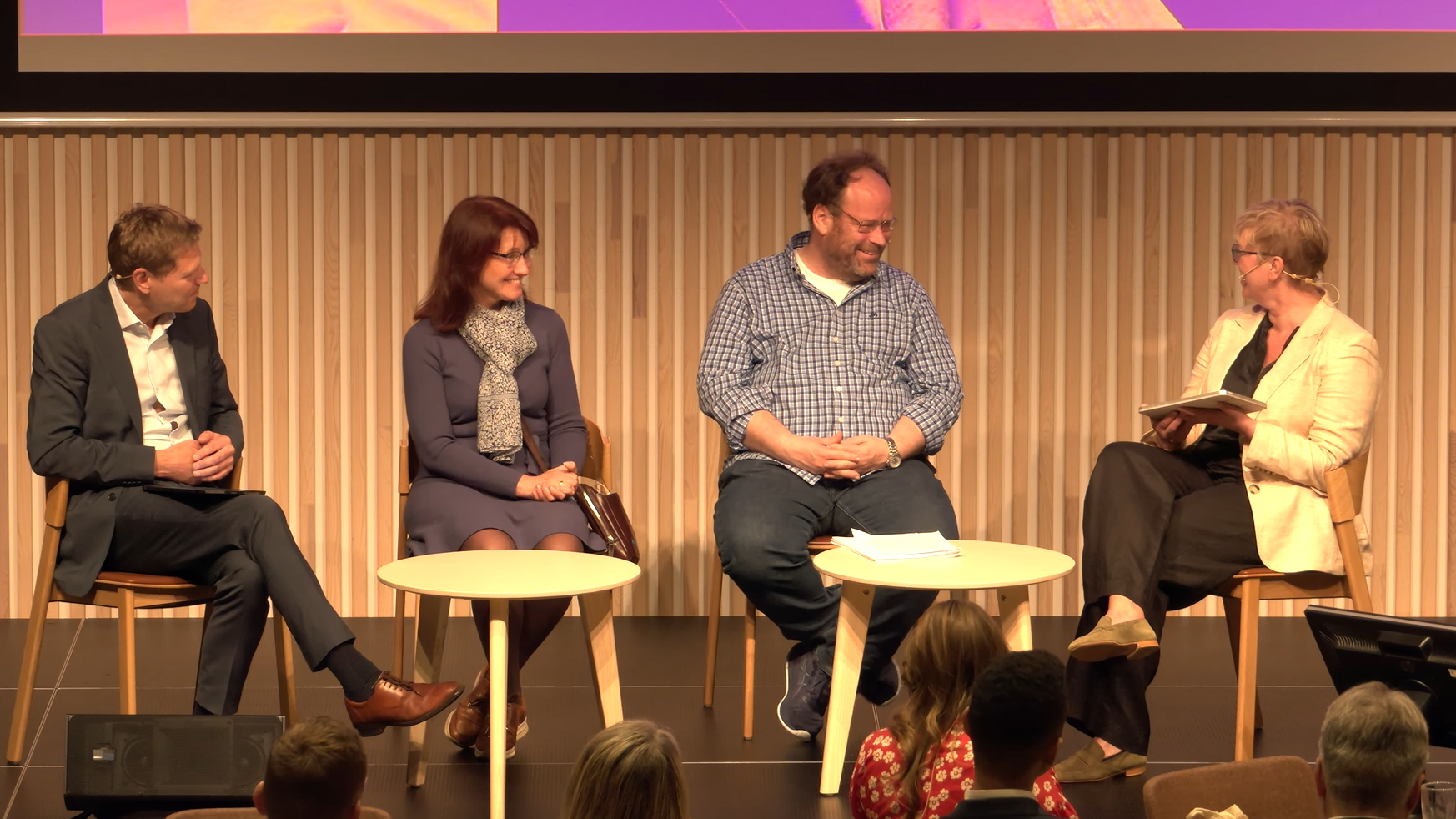 En scene med to menn og to kvinner som snakker sammen og smiler