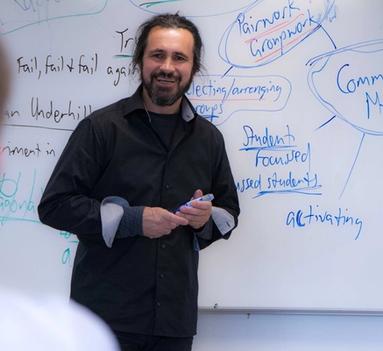 En mann i halvprofil står foran en tavle.