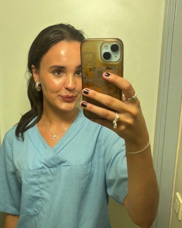 Emmy Wang tar et speilbilde iført arbeidsklær fra Nordseterhjemmet.