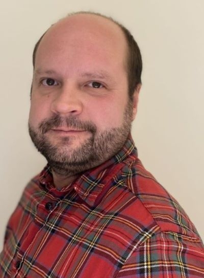 Mann i rutete skjorte ser alvorlig mot kamera
